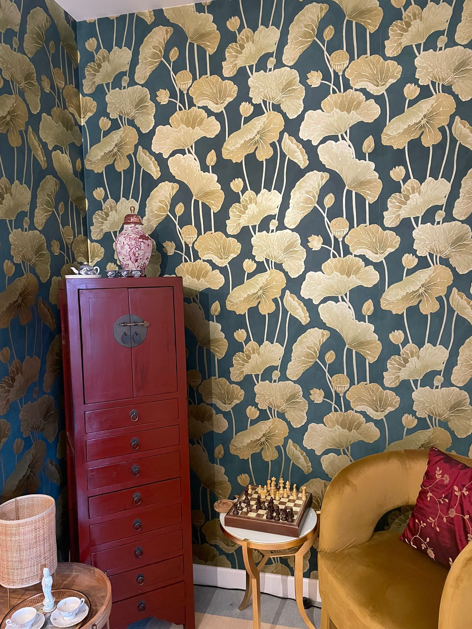 Camera da letto con murale floreale, comodino con vaso, orologio e biancheria da letto bianca.