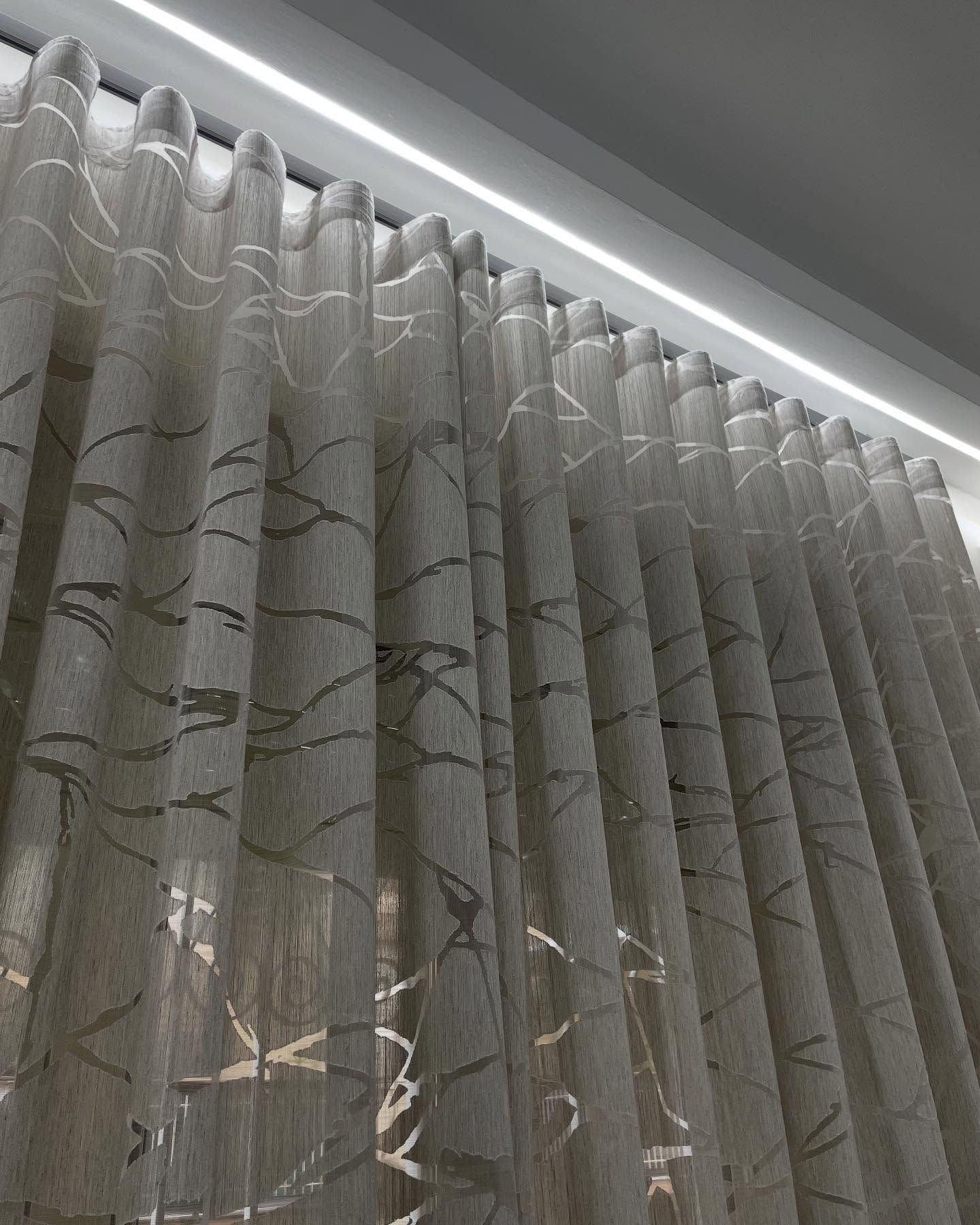 Tende a fantasia beige appese a un binario con una lampada sopraelevata.