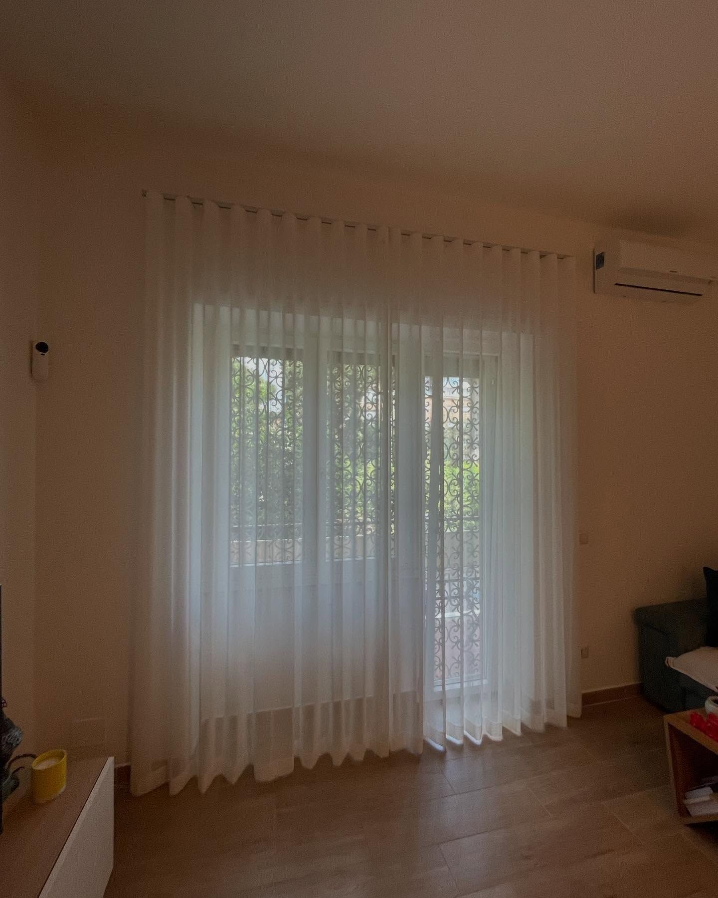 Tende bianche trasparenti coprono una finestra e una porta.