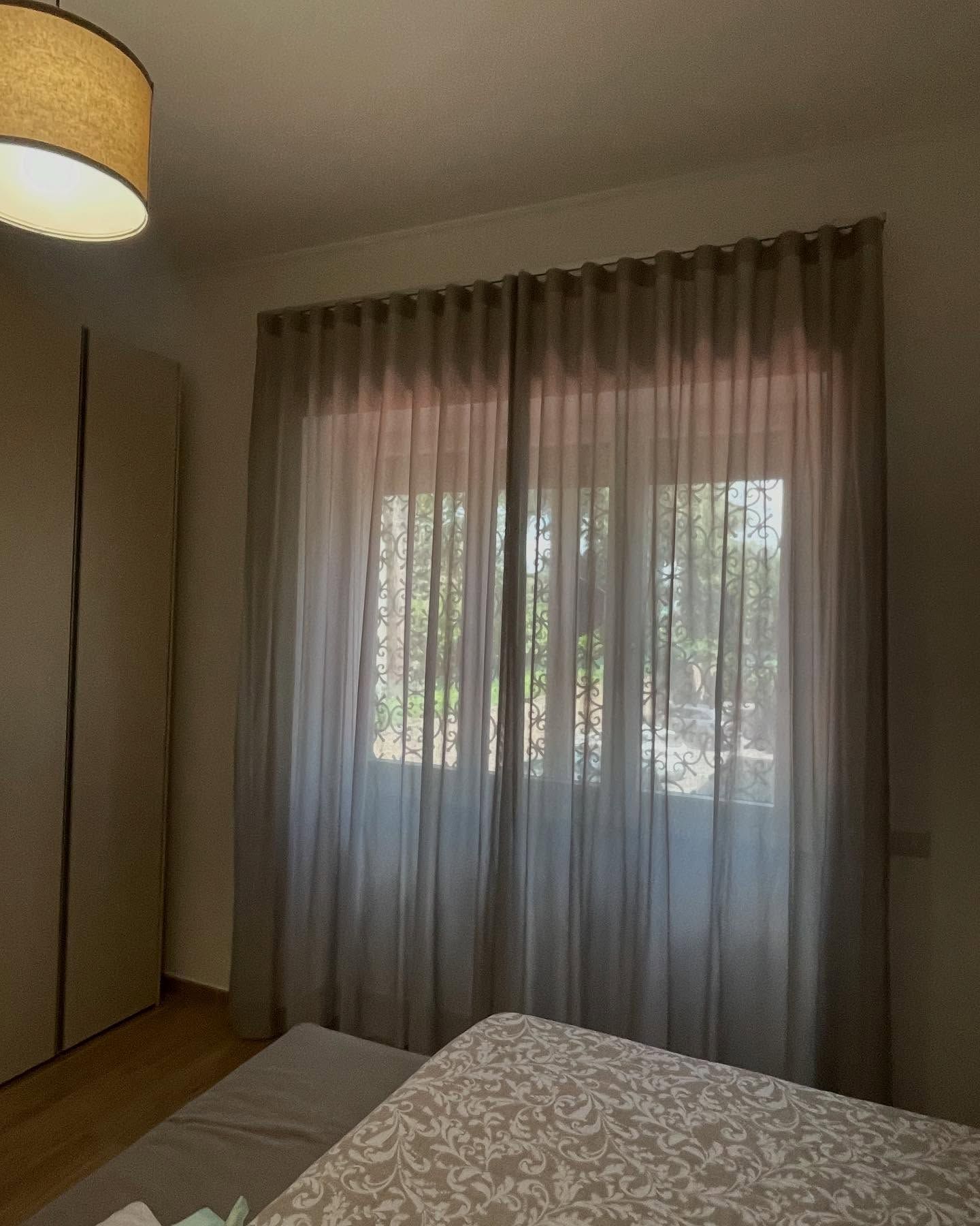 Camera da letto con tende grigie trasparenti sopra una finestra