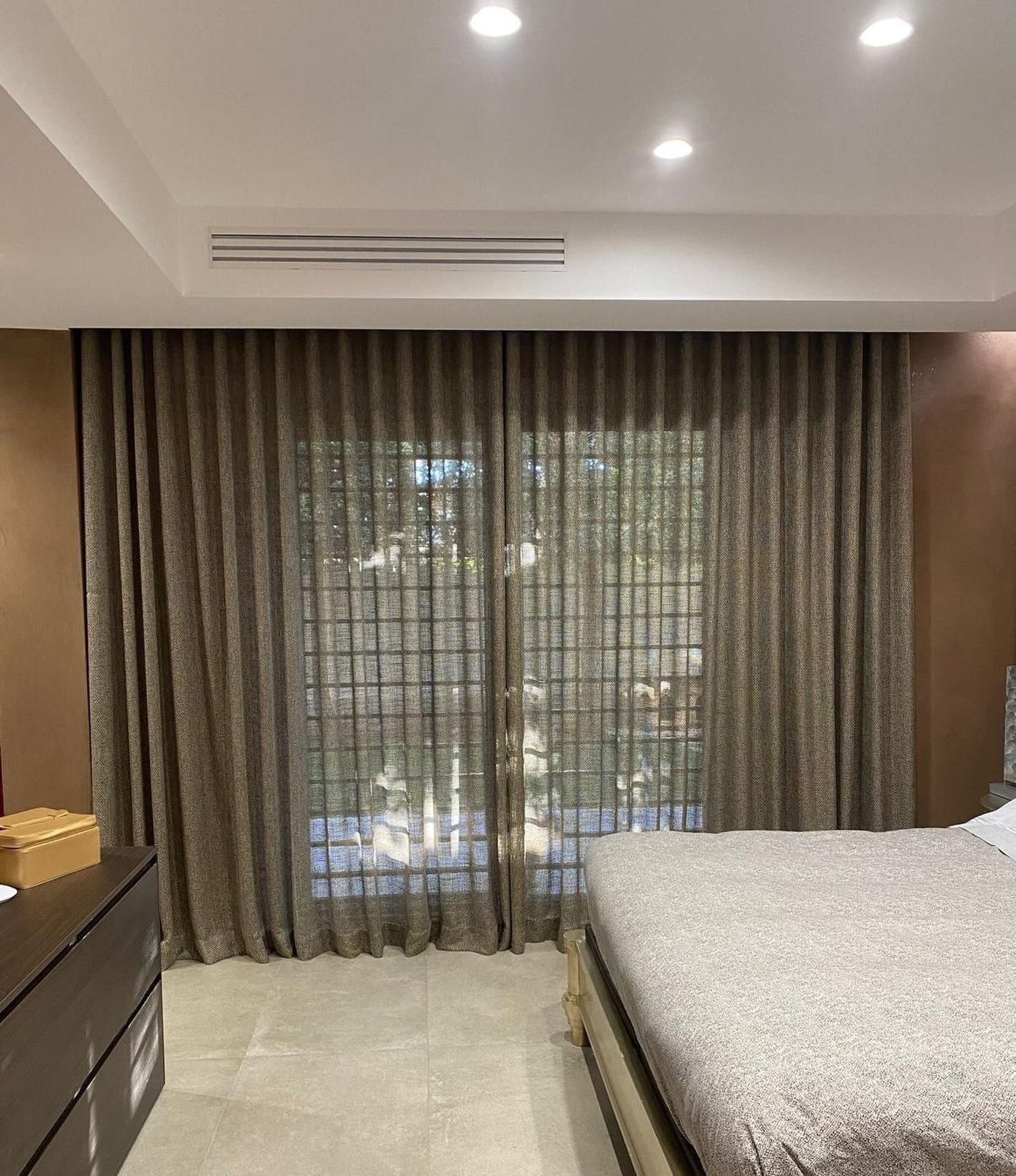 Camera da letto con tende color cuoio, pannelli trasparenti e un letto.