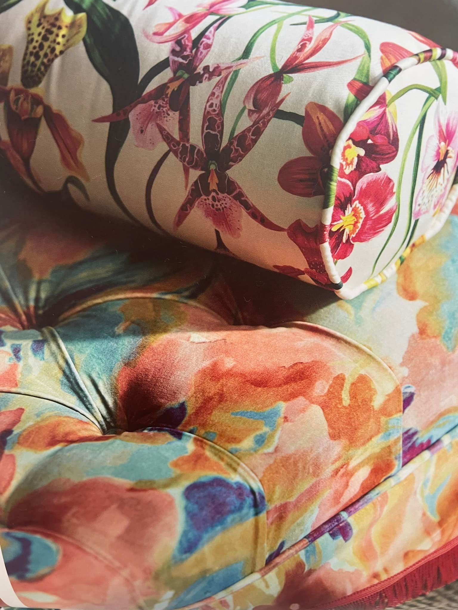 Cuscino a rullo con motivo floreale su un cuscino da seduta con bottoni e un colorato disegno astratto.