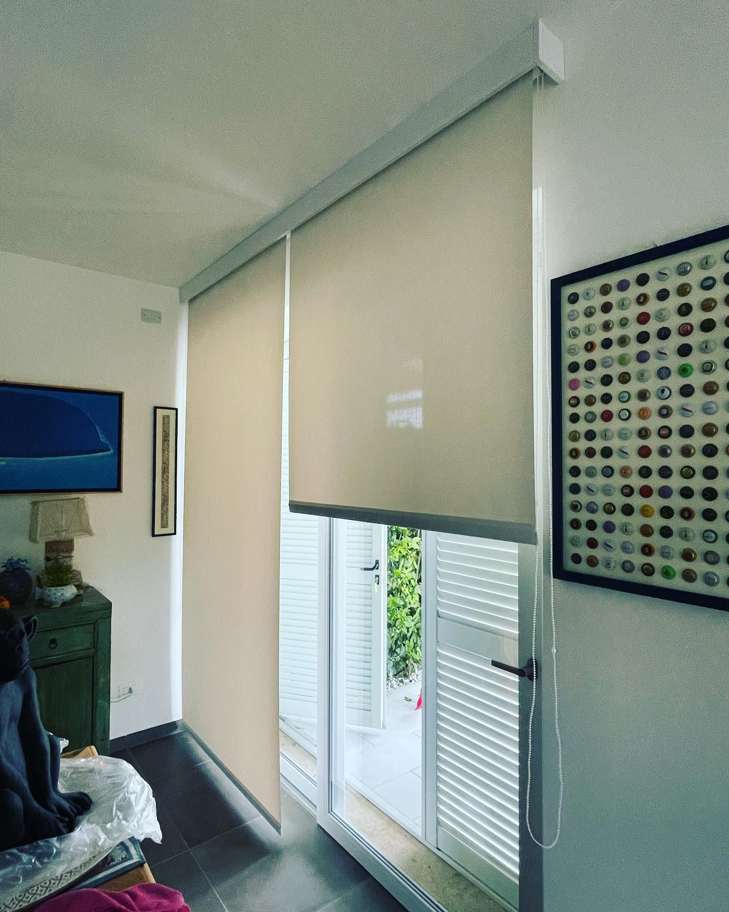 Vista interna: le tende a rullo color cuoio coprono parzialmente la finestra e la porta.