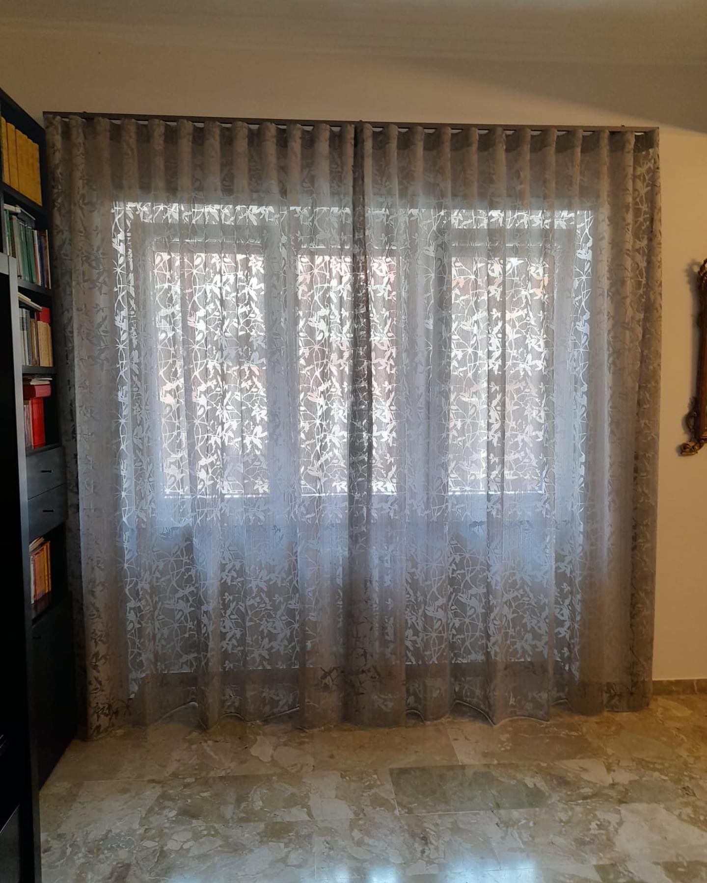 Finestra con tende trasparenti e fantasia; la luce del sole filtra attraverso.