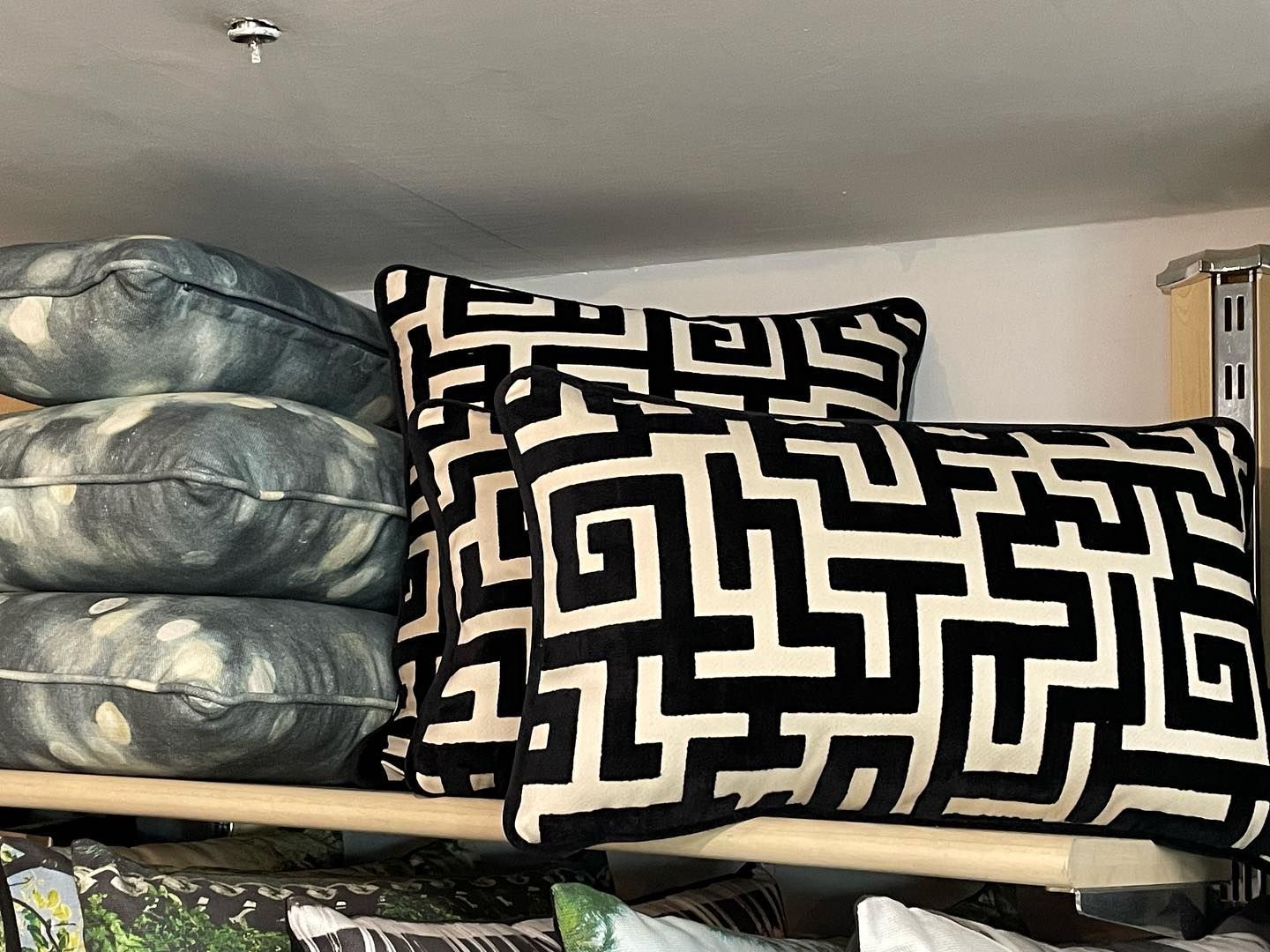 Cuscini impilati su uno scaffale. Cuscini con motivi geometrici bianchi e neri e cuscini con motivi grigi.