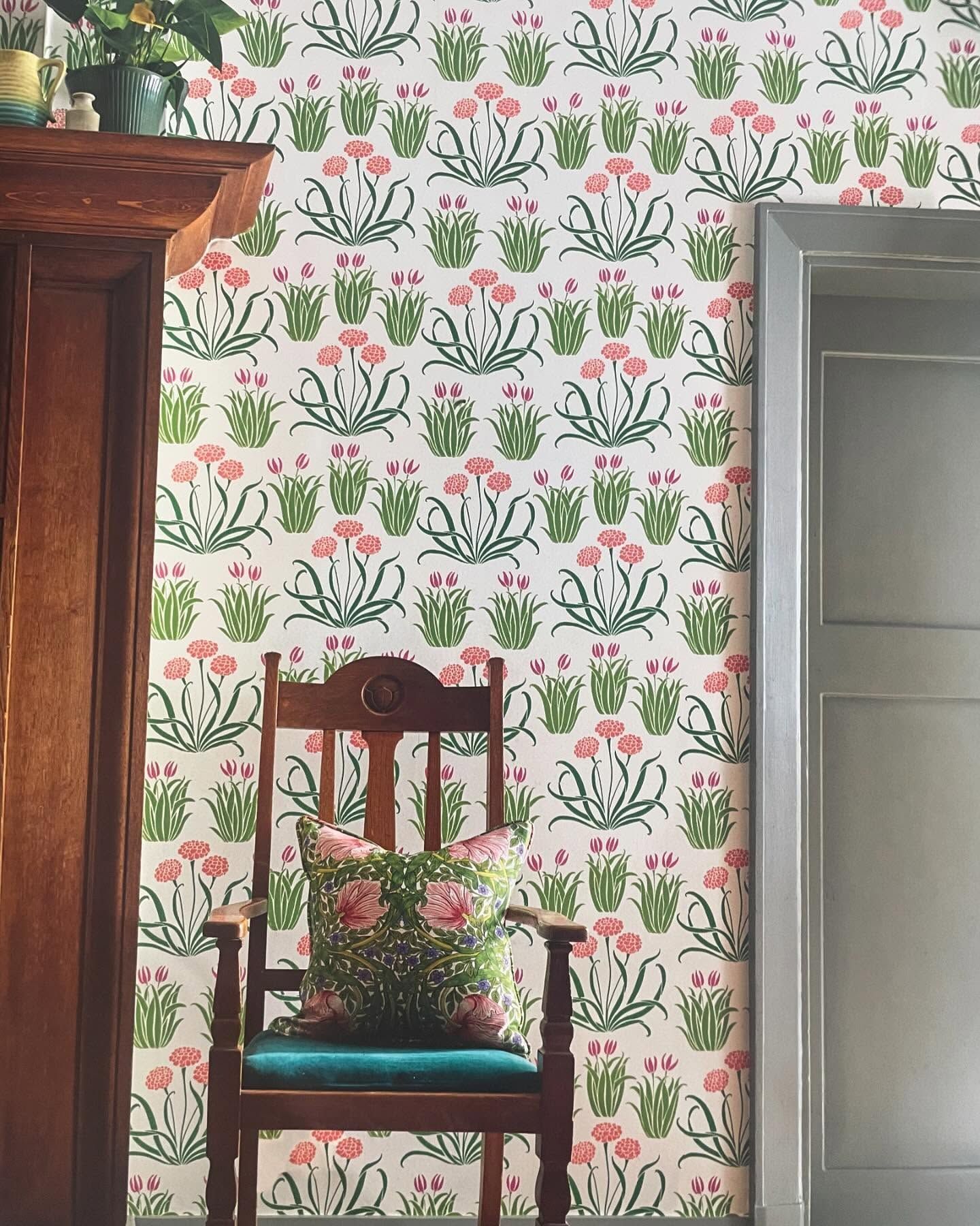 Carta da parati floreale, sedia in legno con cuscino floreale e stipite della porta in legno.