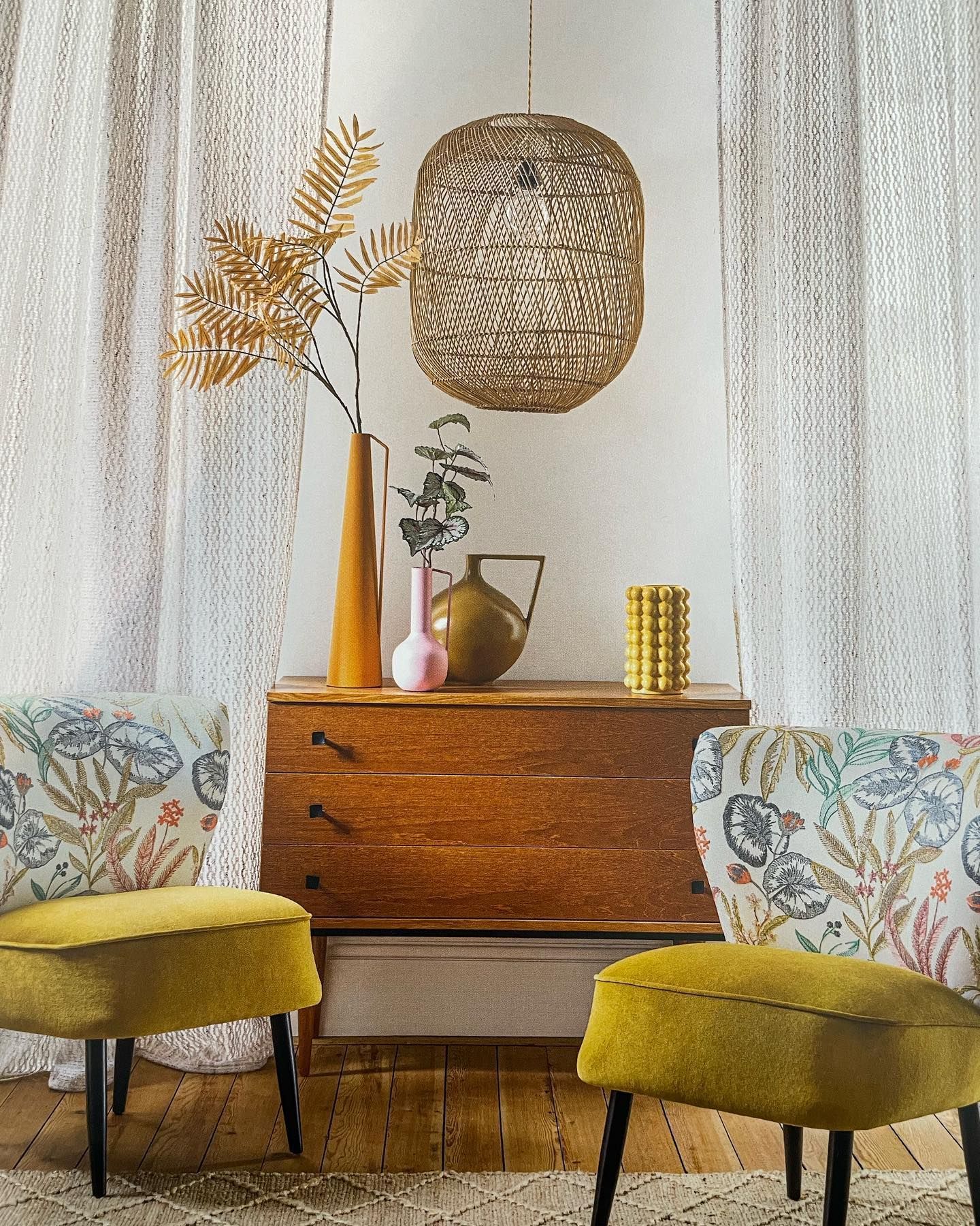 Scena di soggiorno con una cassapanca di legno, due sedie gialle e oggetti decorativi.