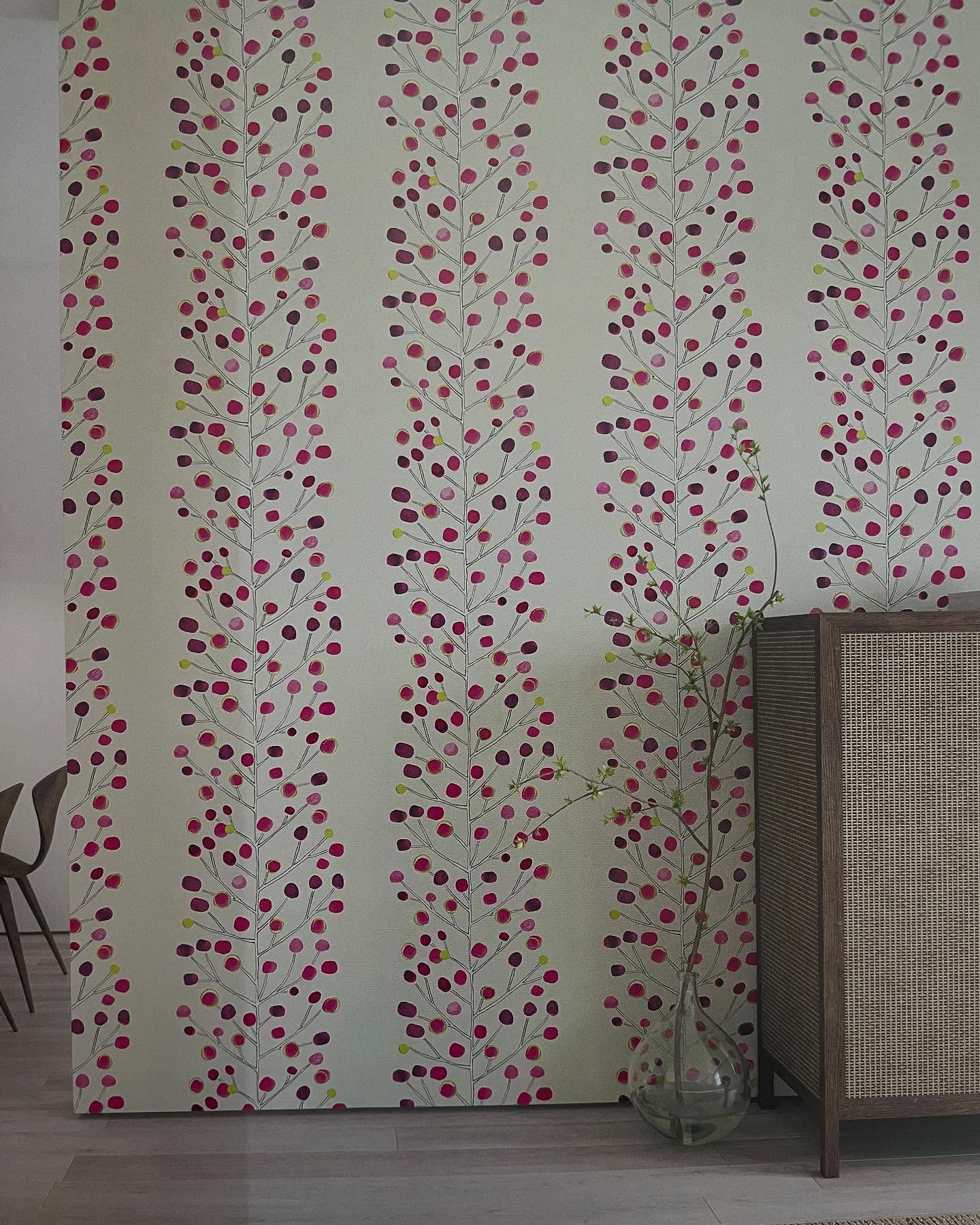 Carta da parati con strisce verticali di piccoli motivi floreali rossi e viola.