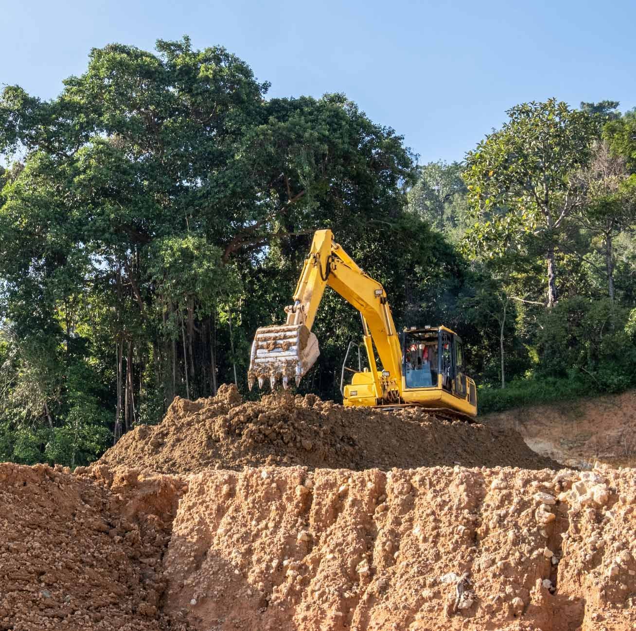 A yellow excavator is working on a pile of dirt.