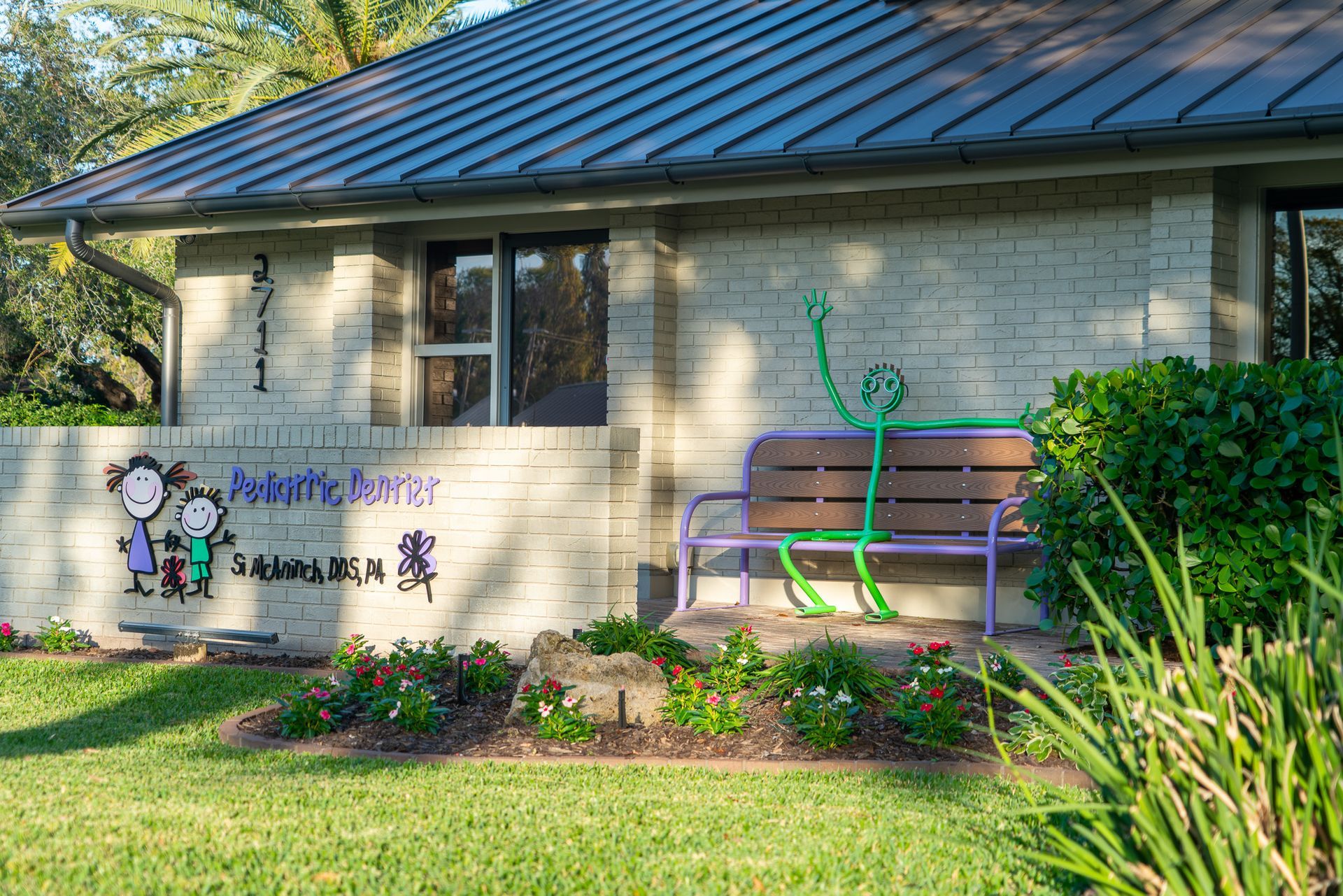 A white brick house with a purple bench in front of it.