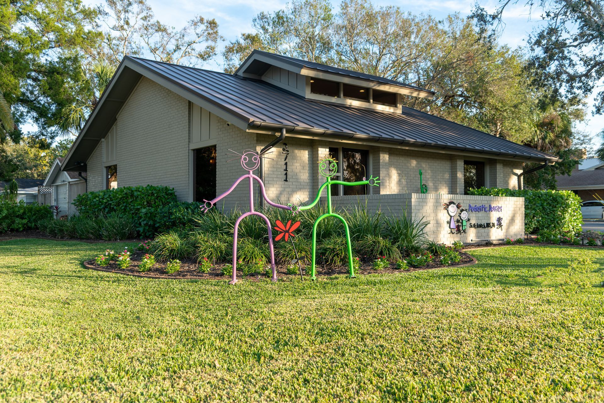 A house with a black roof and a sculpture in front of it.