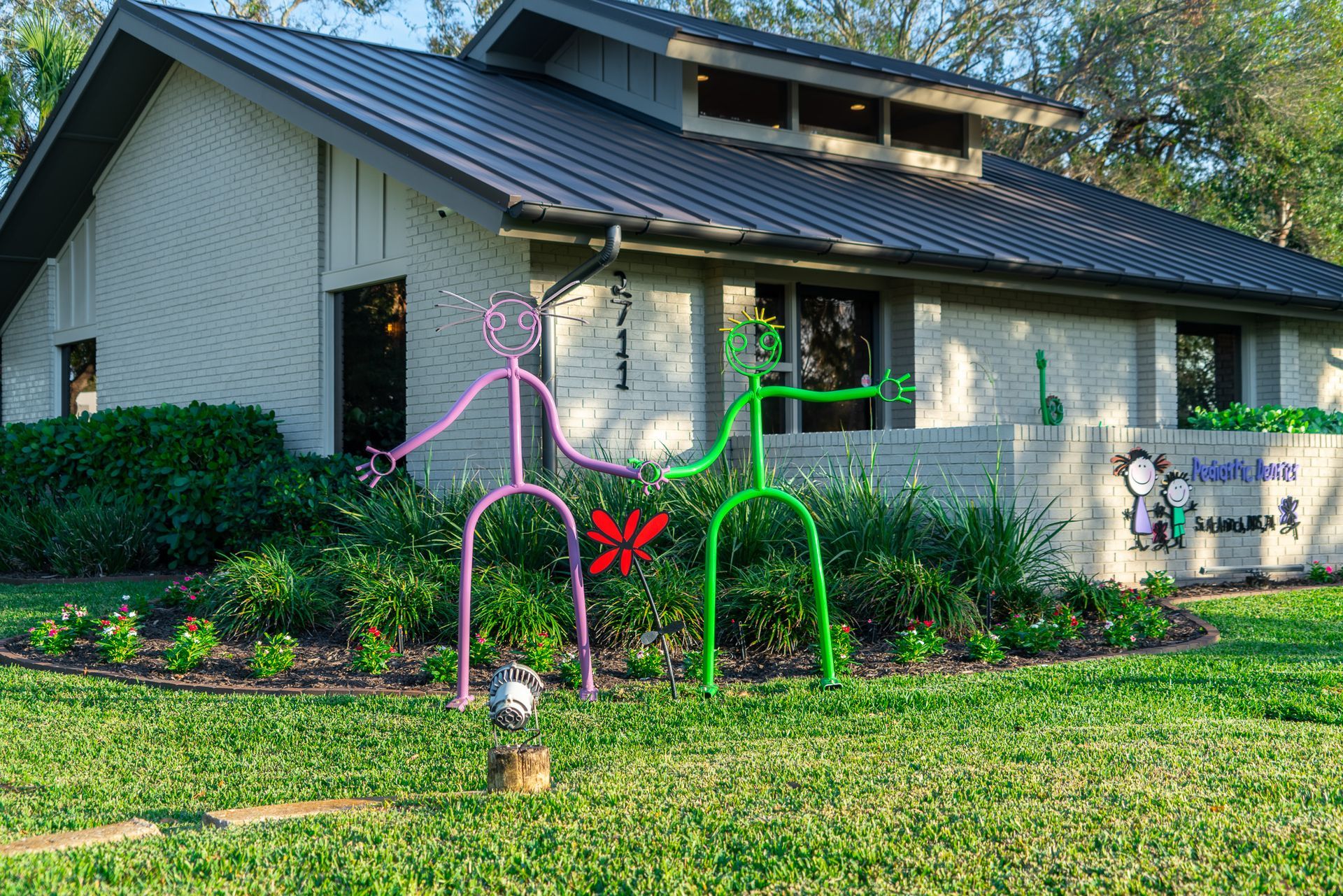 A white house with a black roof and a sculpture in front of it