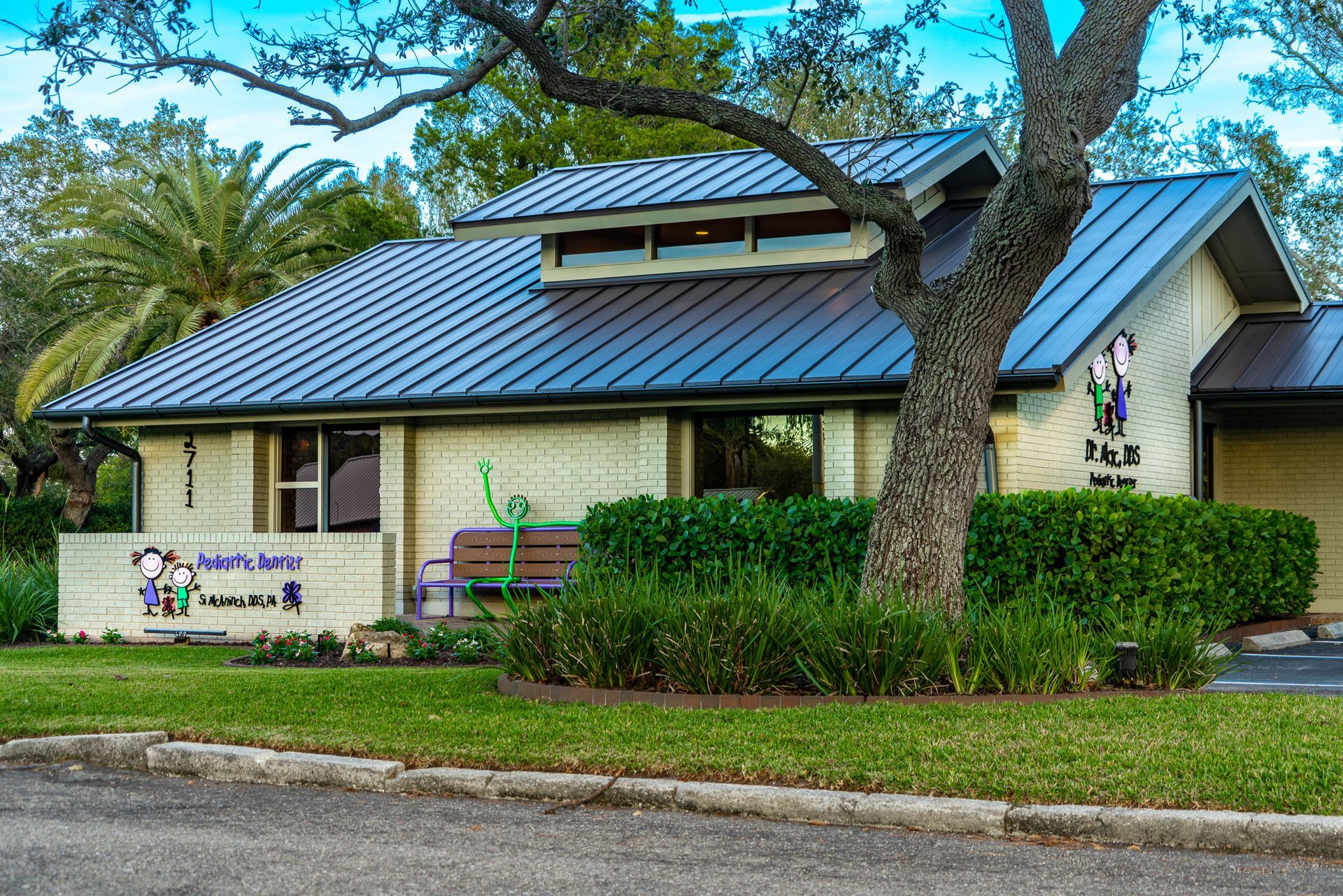 A white house with a blue roof and a tree in front of it