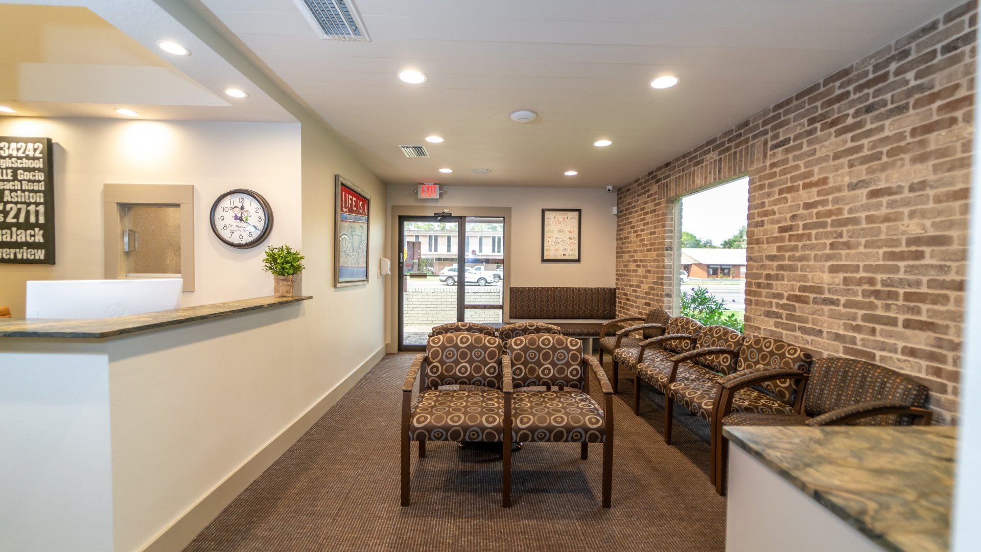 A waiting room with chairs and a brick wall in a dental office.