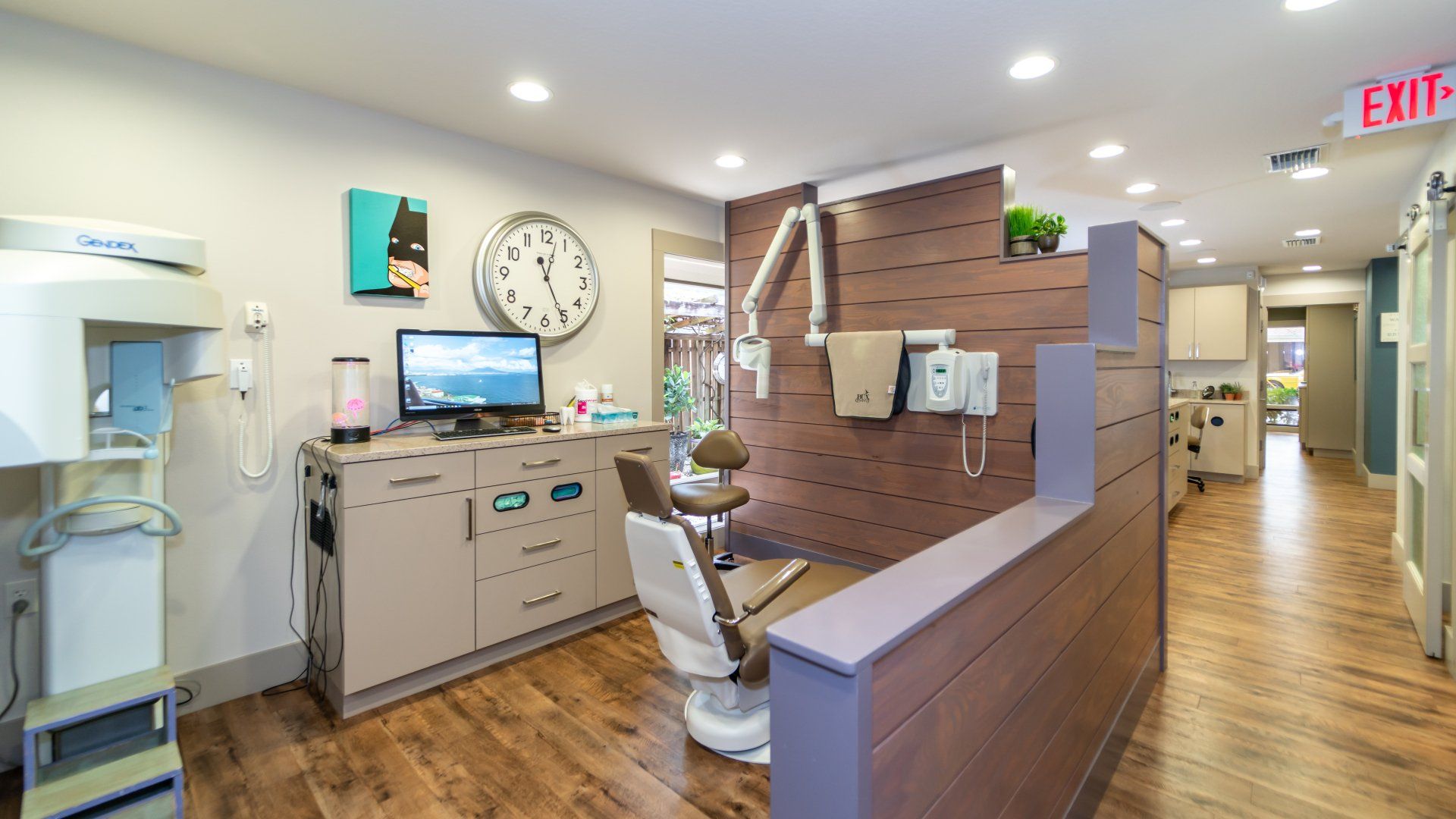 A dental office with a clock on the wall and a dental chair.