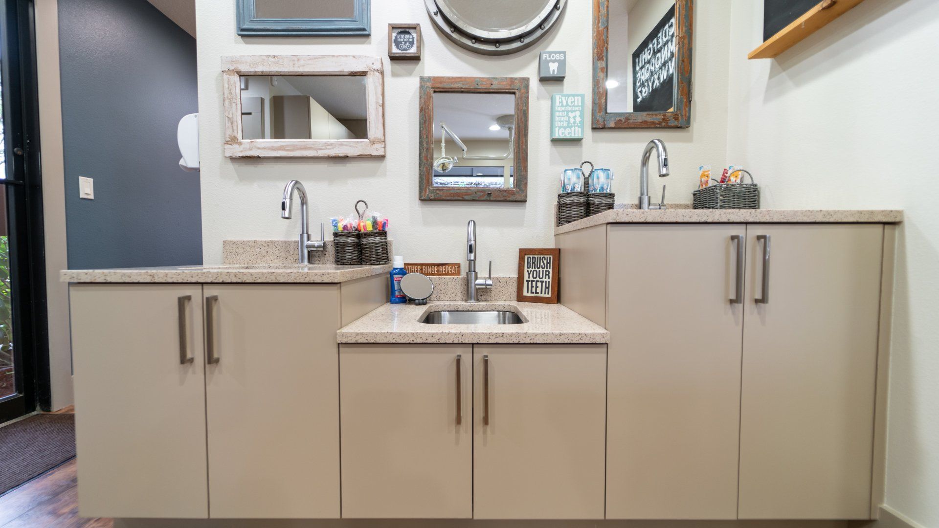 A kitchen with a sink and cabinets and mirrors on the wall.