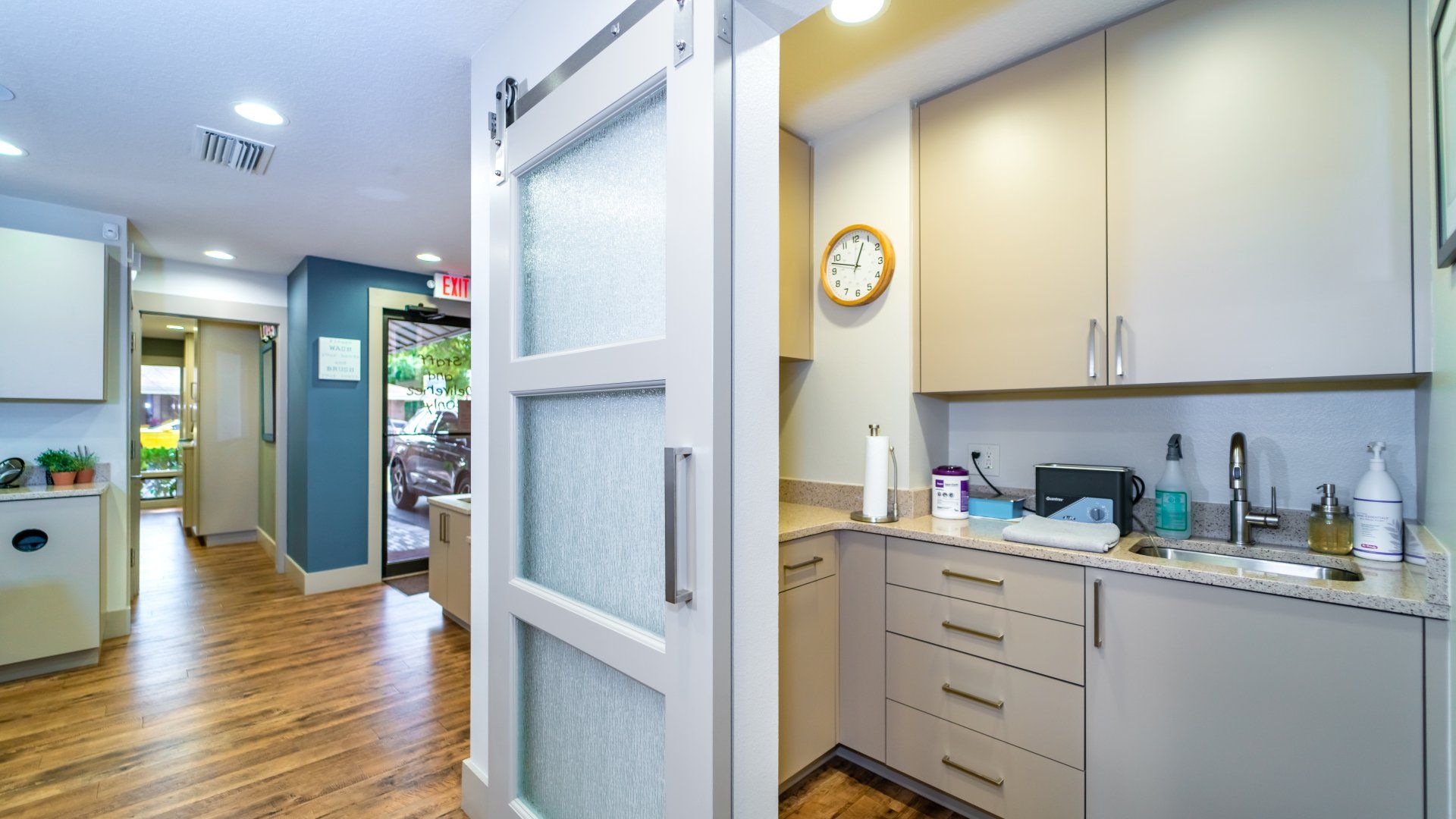 A kitchen with a clock on the wall and a sliding barn door.