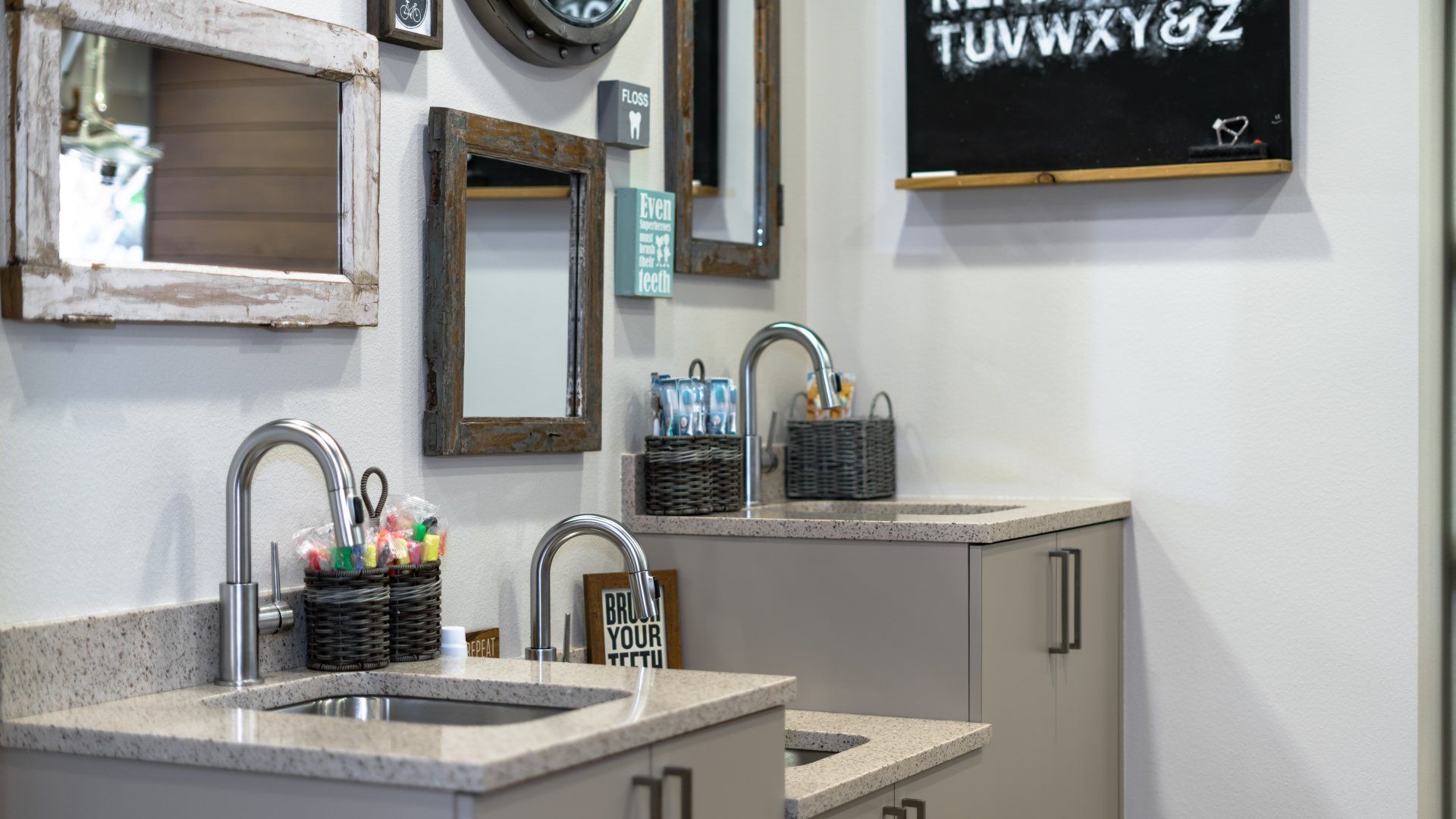 A bathroom with a sink , mirrors , and a chalkboard on the wall.