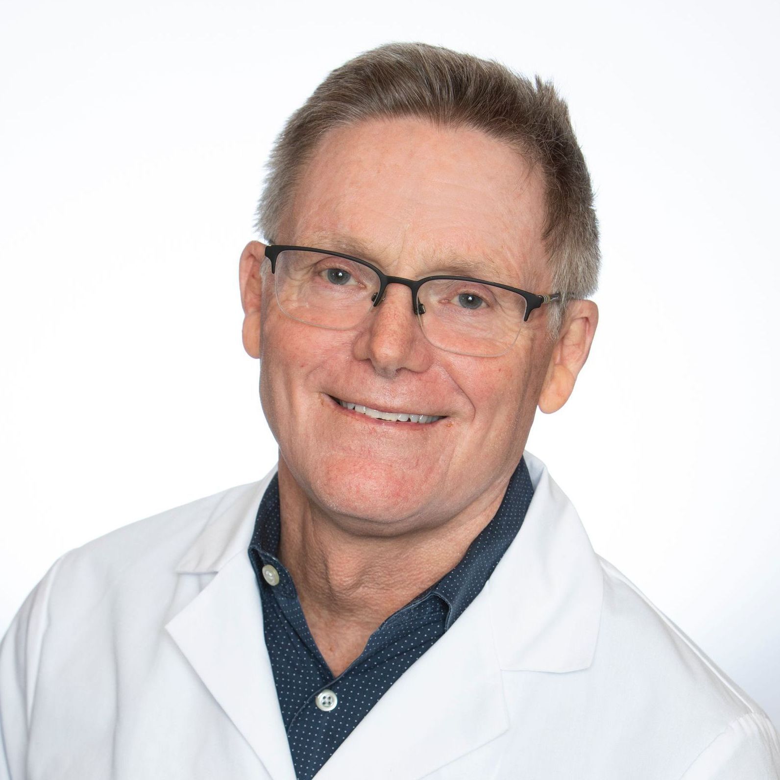A woman wearing a black shirt and a black vest is smiling for the camera.