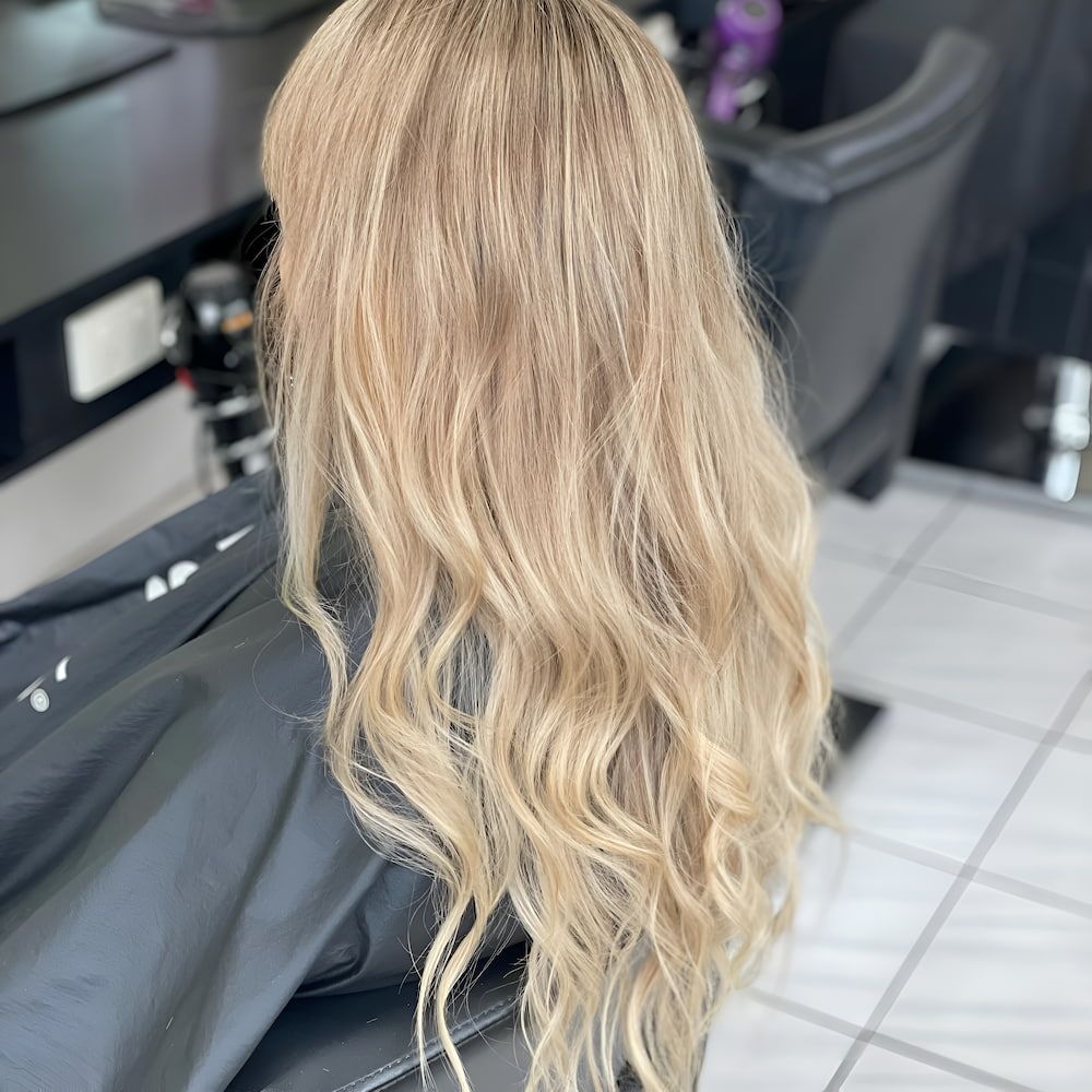 A Woman With Long Blonde Hair Is Sitting In A Chair In A Salon — Howard Street Hair Studio In Nambour, QLD