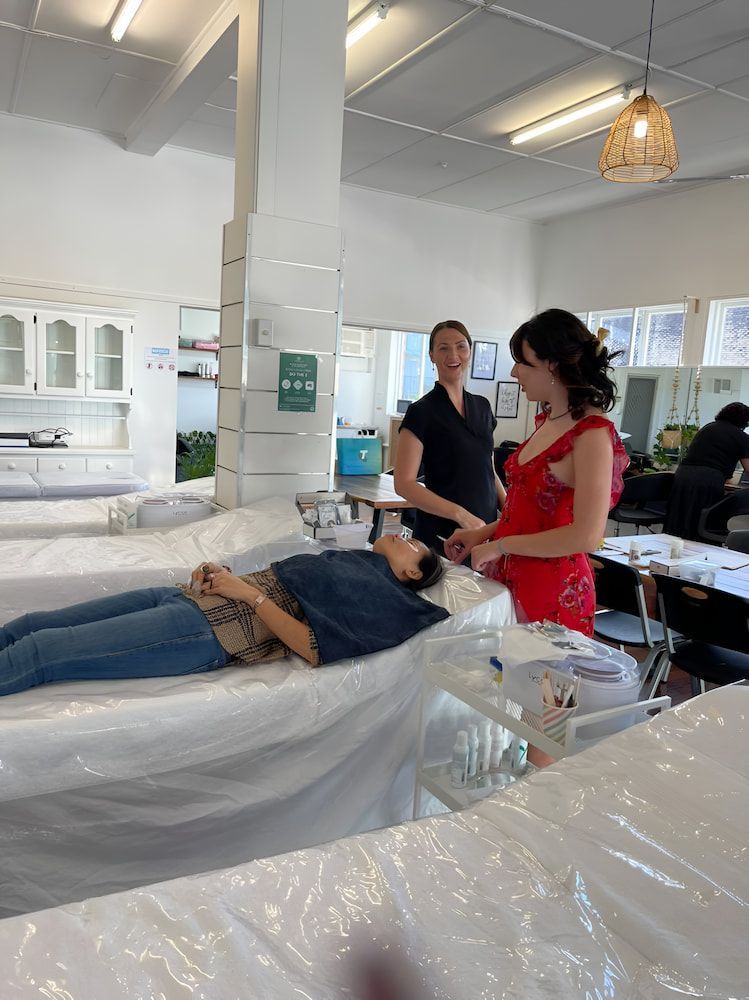 A Woman In A Red Dress Is Laying On A Bed In A Room With Other People — Howard Street Hair Studio In Nambour, QLD