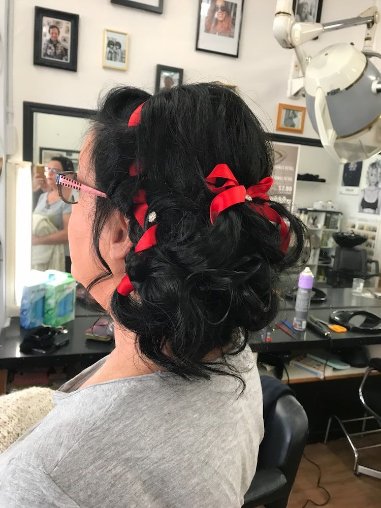 A Woman Is Sitting In A Chair With Her Hair In A Bun With A Red Bow — Howard Street Hair Studio In Nambour, QLD