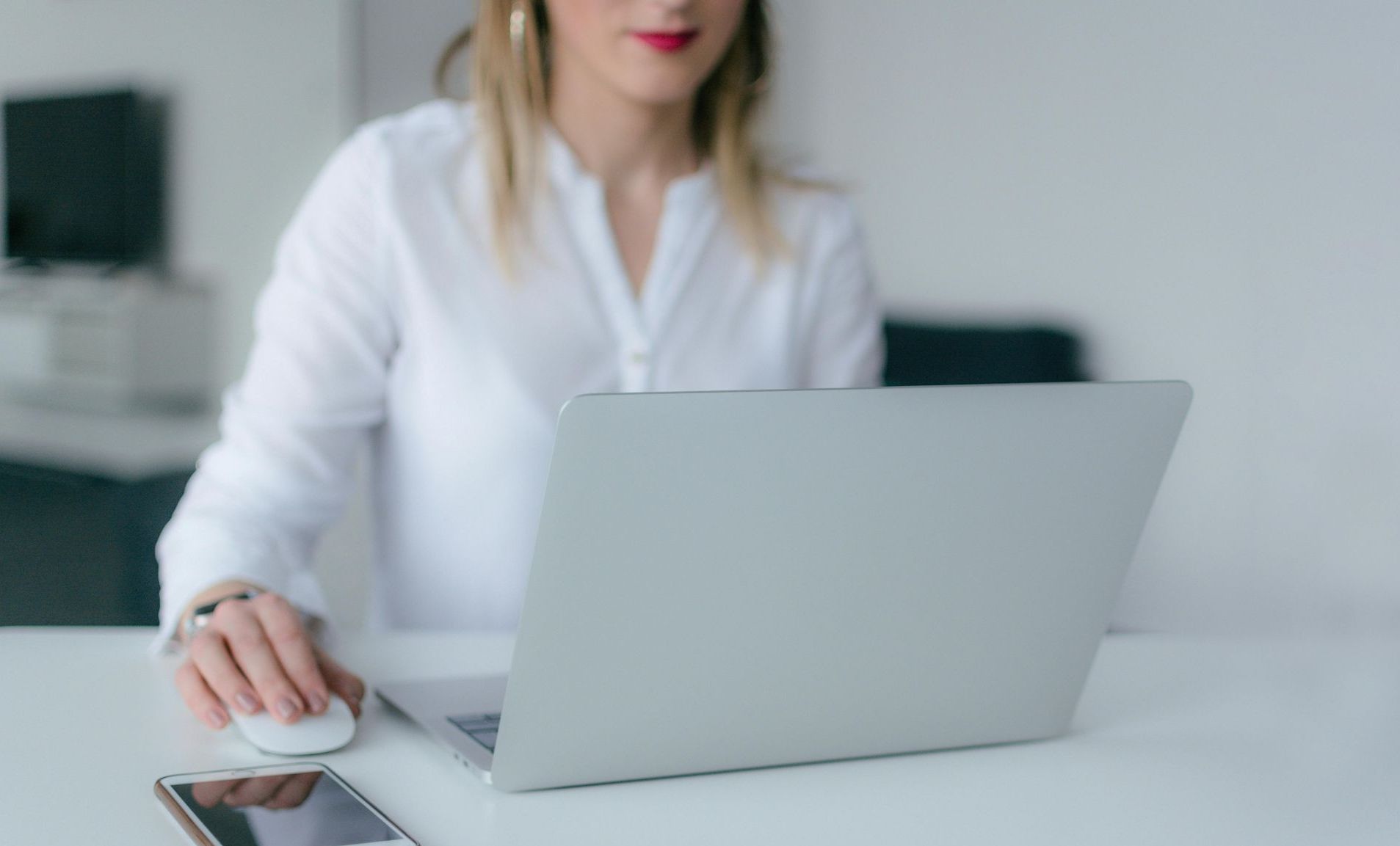 A woman is sitting at a desk using a laptop computer.