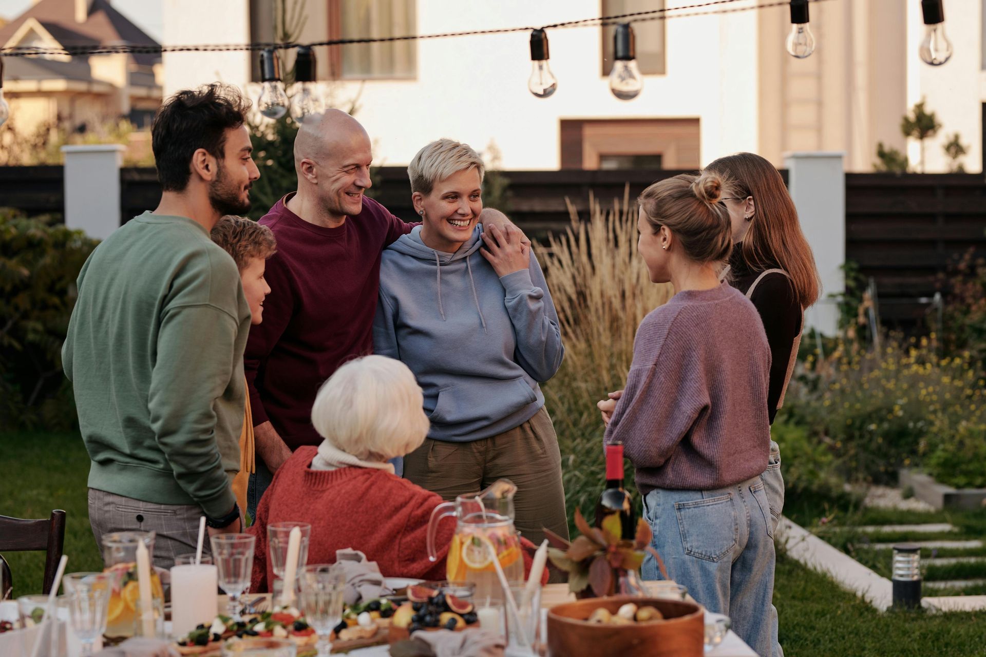 A group of people are standing around a table with food.