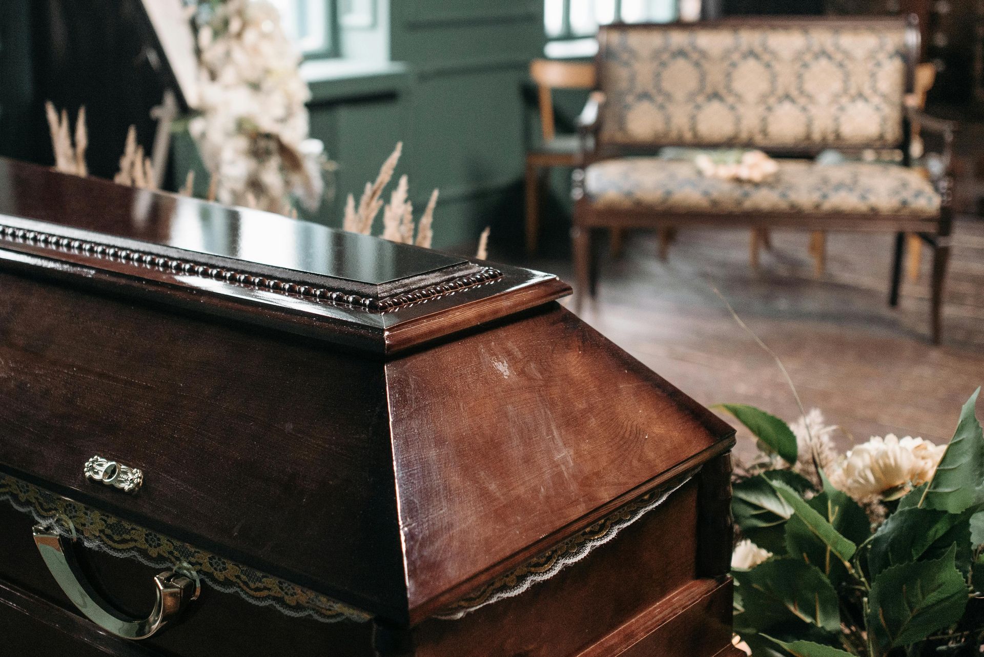 A wooden coffin is sitting in a room next to flowers.