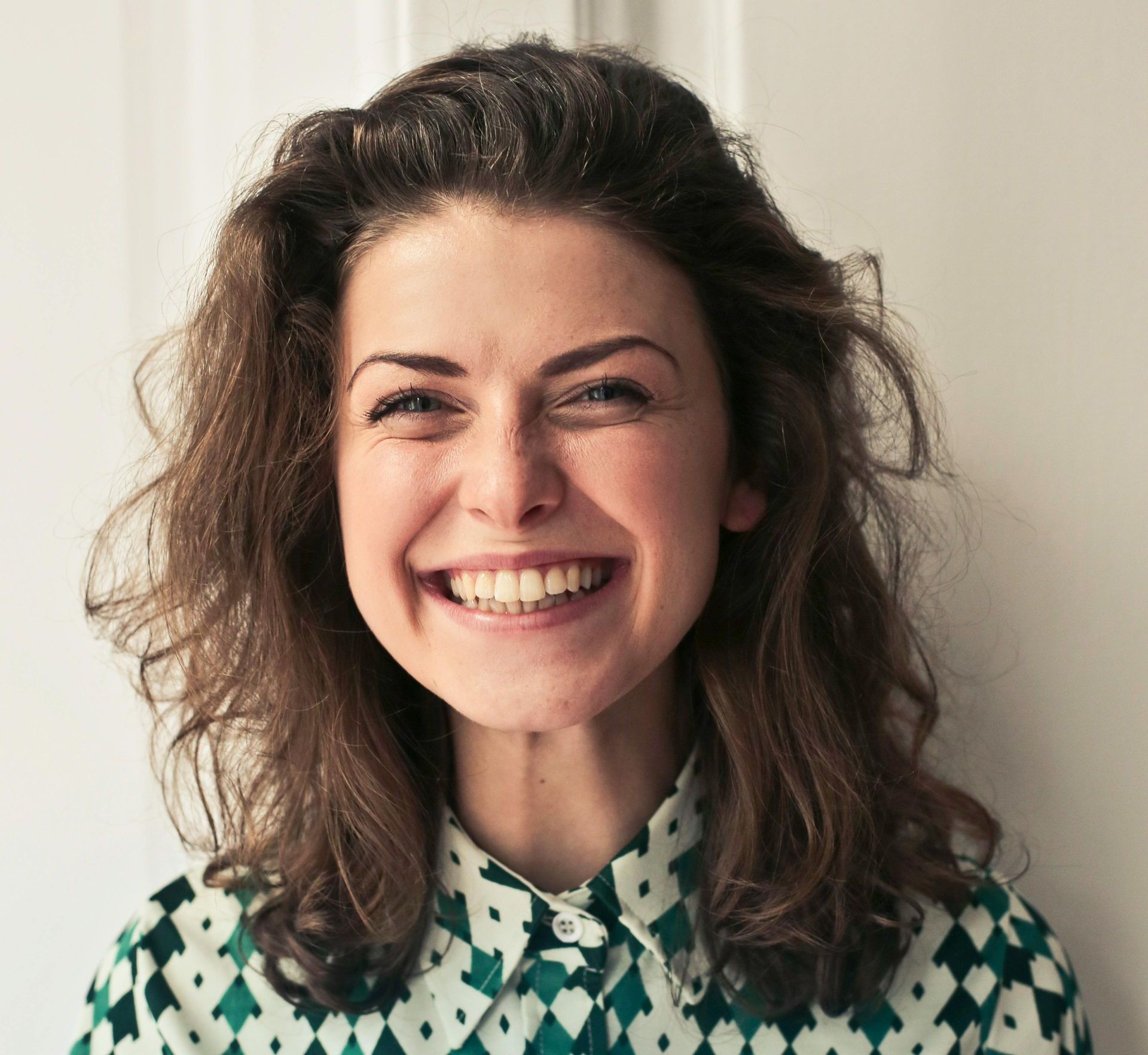 A woman in a green and white shirt is smiling