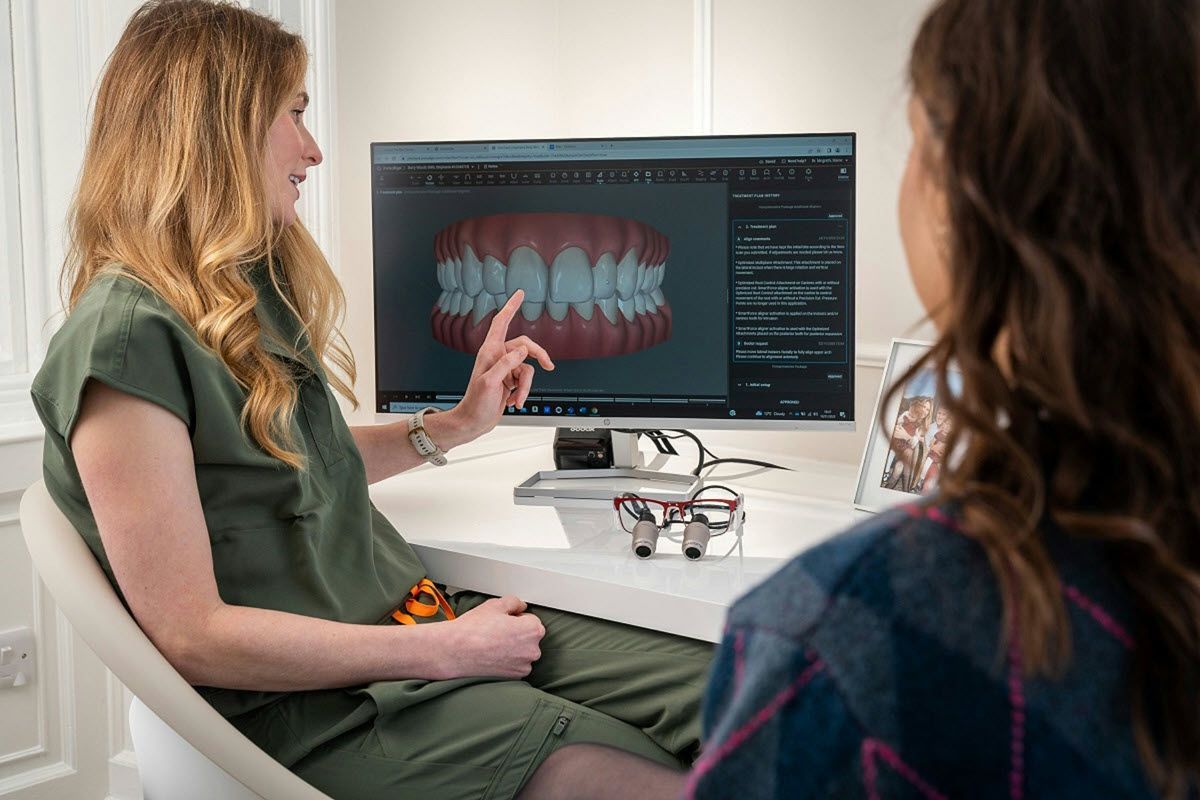 Woman pointing at teeth model on a computer screen for a patient at a dental office.