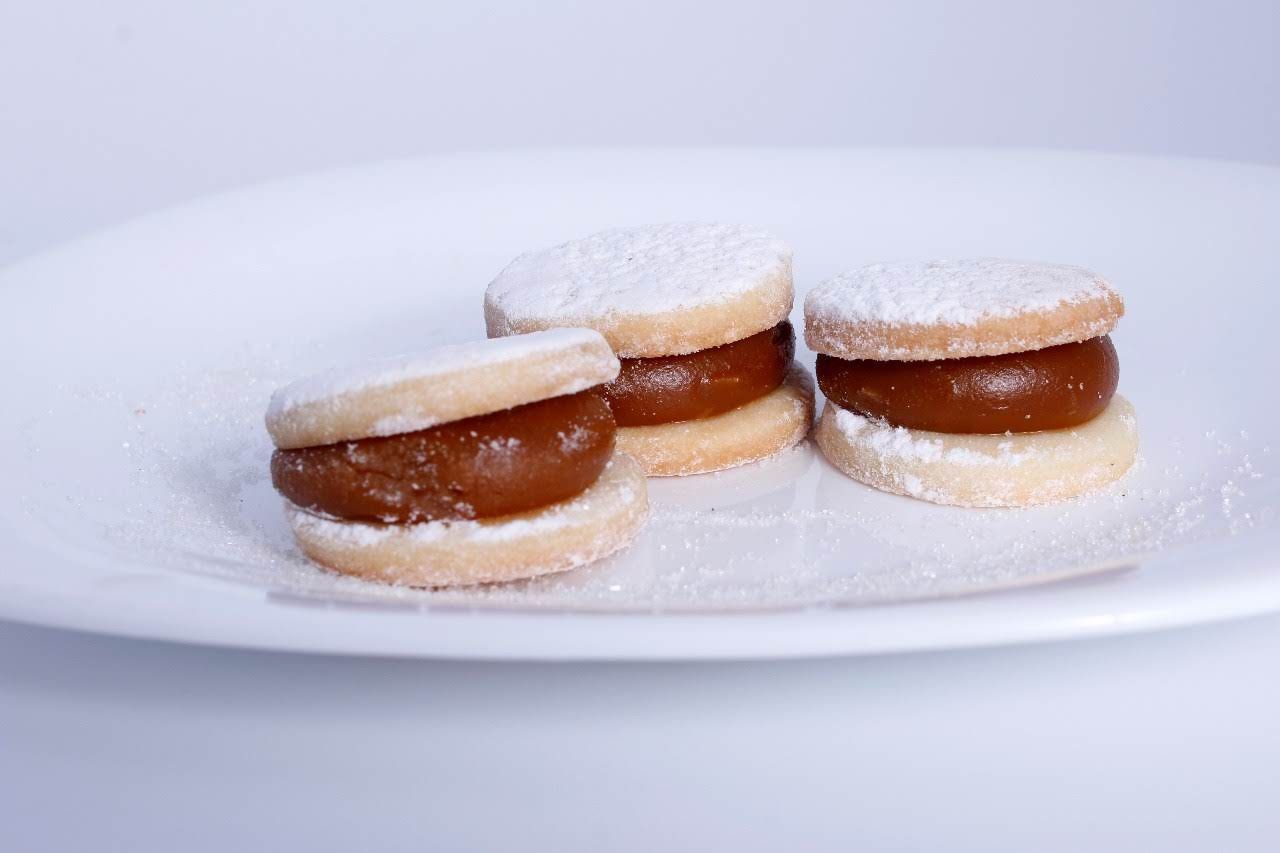Tres galletas sándwich de azúcar glas rellenas de caramelo en un plato blanco.