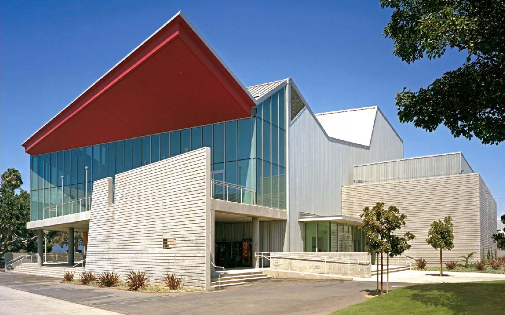 Large modern industrial building with gray and white facade under a blue sky.
