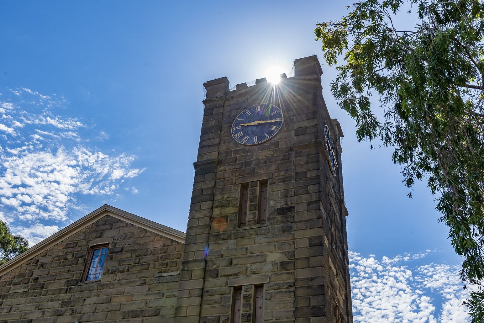 Dramatic view looking up at the stone Benicia clock tower with the sun peeking over the top