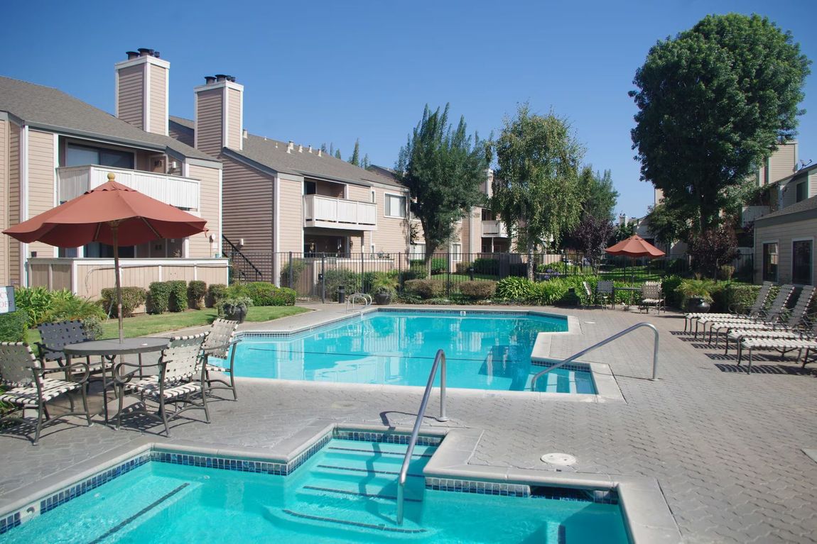 Outdoor apartment pool and hot tub with lounge chairs on a sunny day