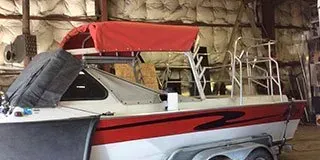 A red and white boat is sitting on a trailer in a warehouse.