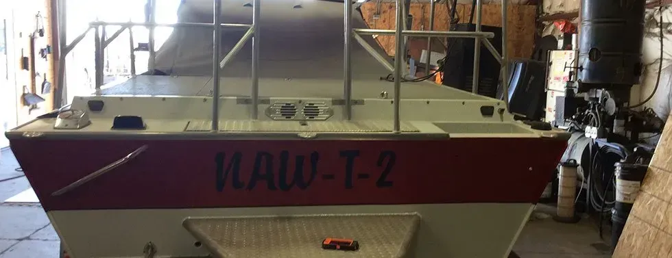 A boat with the name mault-2 on the side is sitting in a garage.