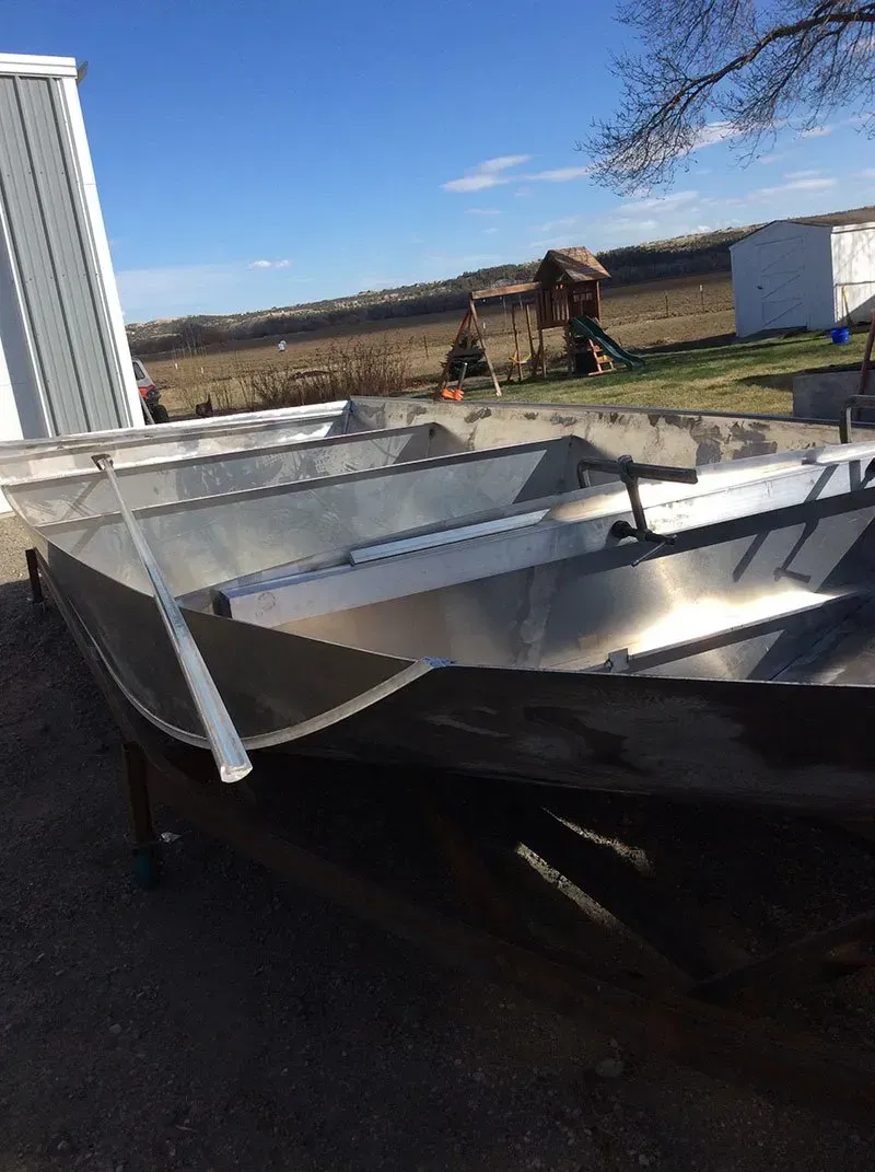 A stainless steel boat is sitting on the ground in a parking lot.