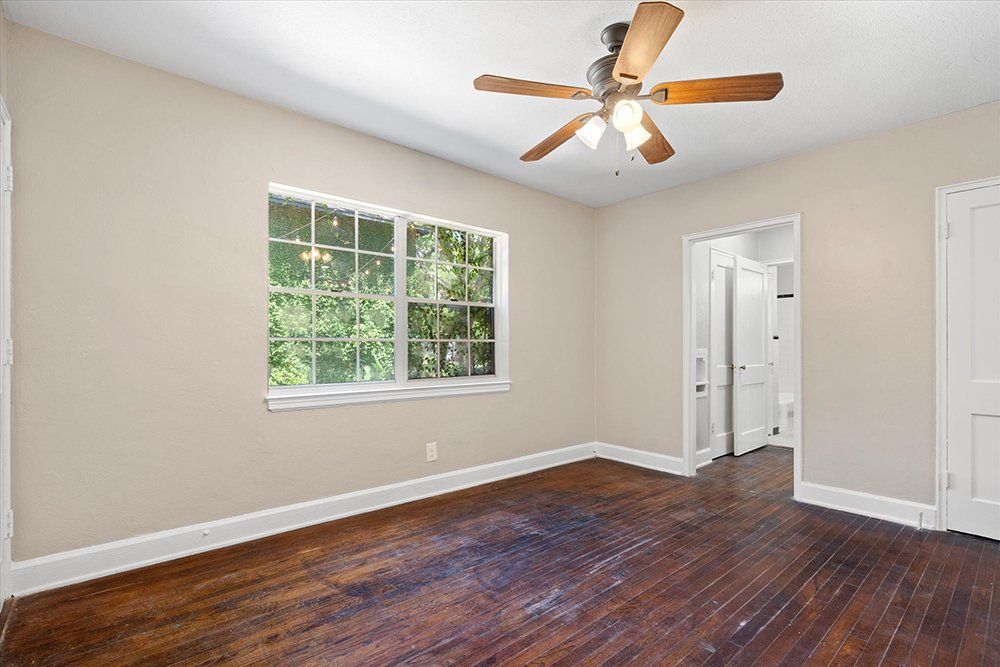 An empty room with hardwood floors and a ceiling fan.