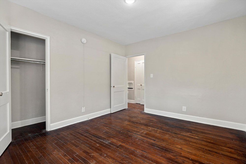 An empty bedroom with hardwood floors and a closet.