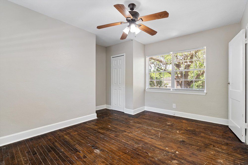 An empty bedroom with hardwood floors and a ceiling fan.