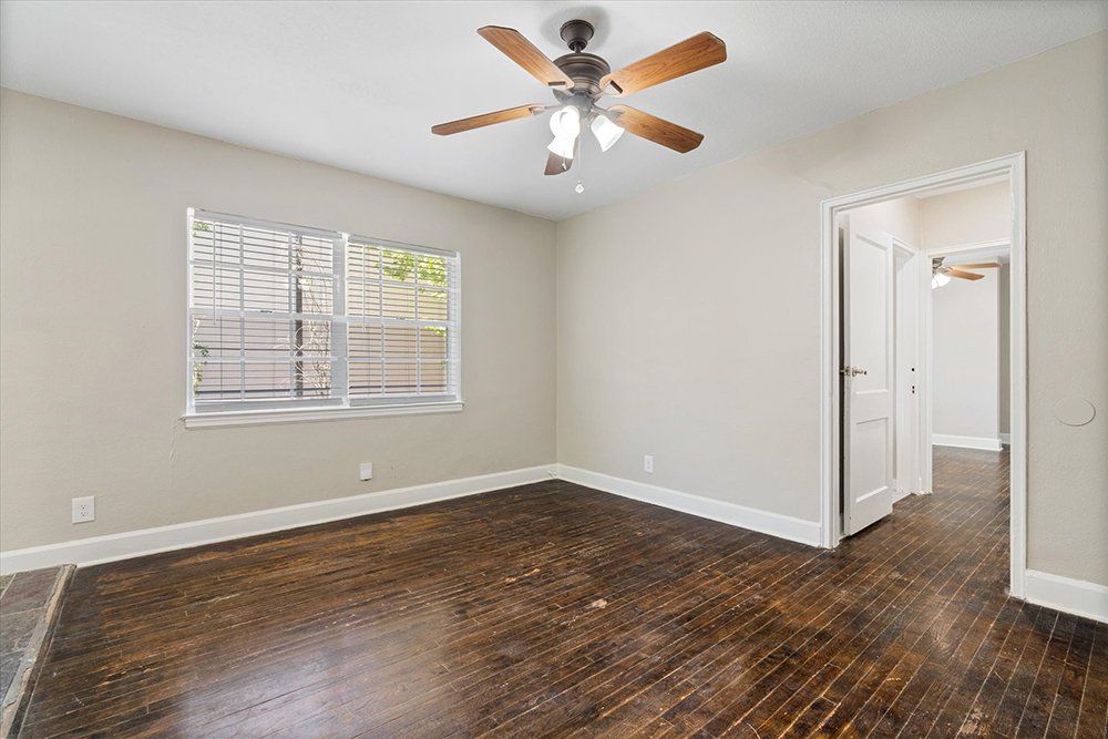 An empty room with hardwood floors and a ceiling fan.