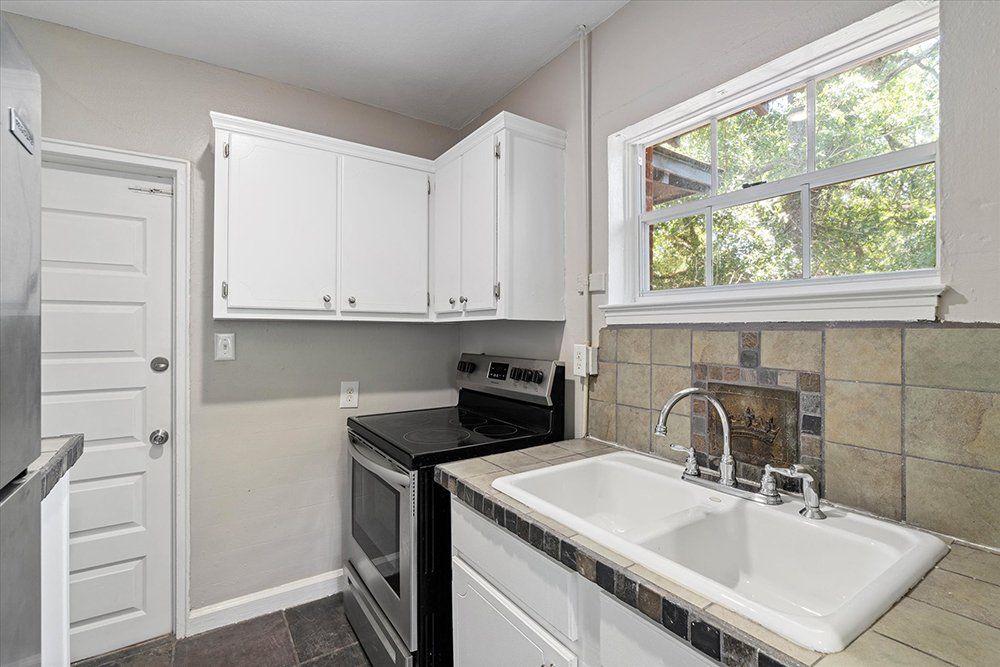 A kitchen with a sink , stove , refrigerator and window.