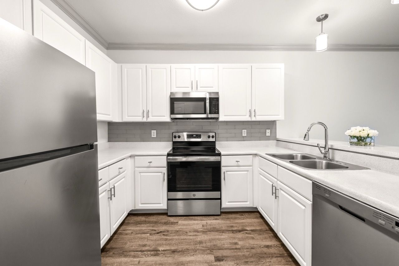 Modern white kitchen with stainless steel stove, microwave, dishwasher, and double sink