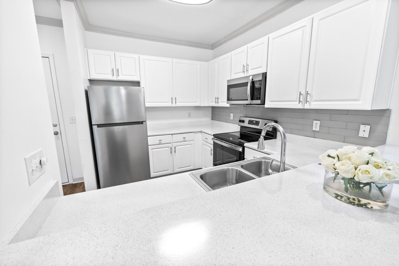 Kitchen in an apartment with white cabinets, stainless steel appliances, and a double-basin sink.
