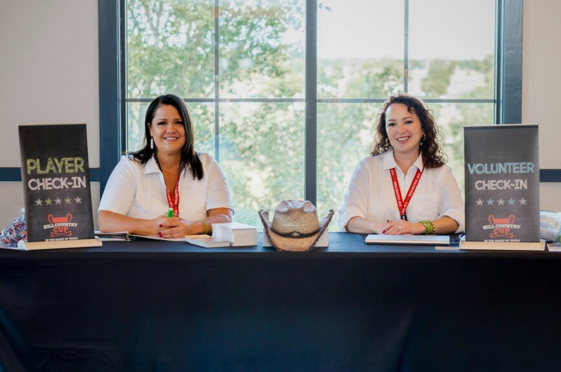 A man wearing a hat and apron is standing in front of a grill.