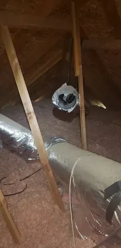 Bowling Heating & Conditioning LLC Spray Foam- A fan is sitting in the attic next to a pipe.