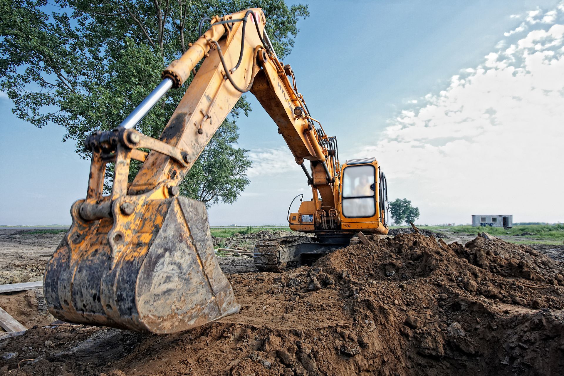 Yellow excavator digging dirt at a construction site under a blue sky