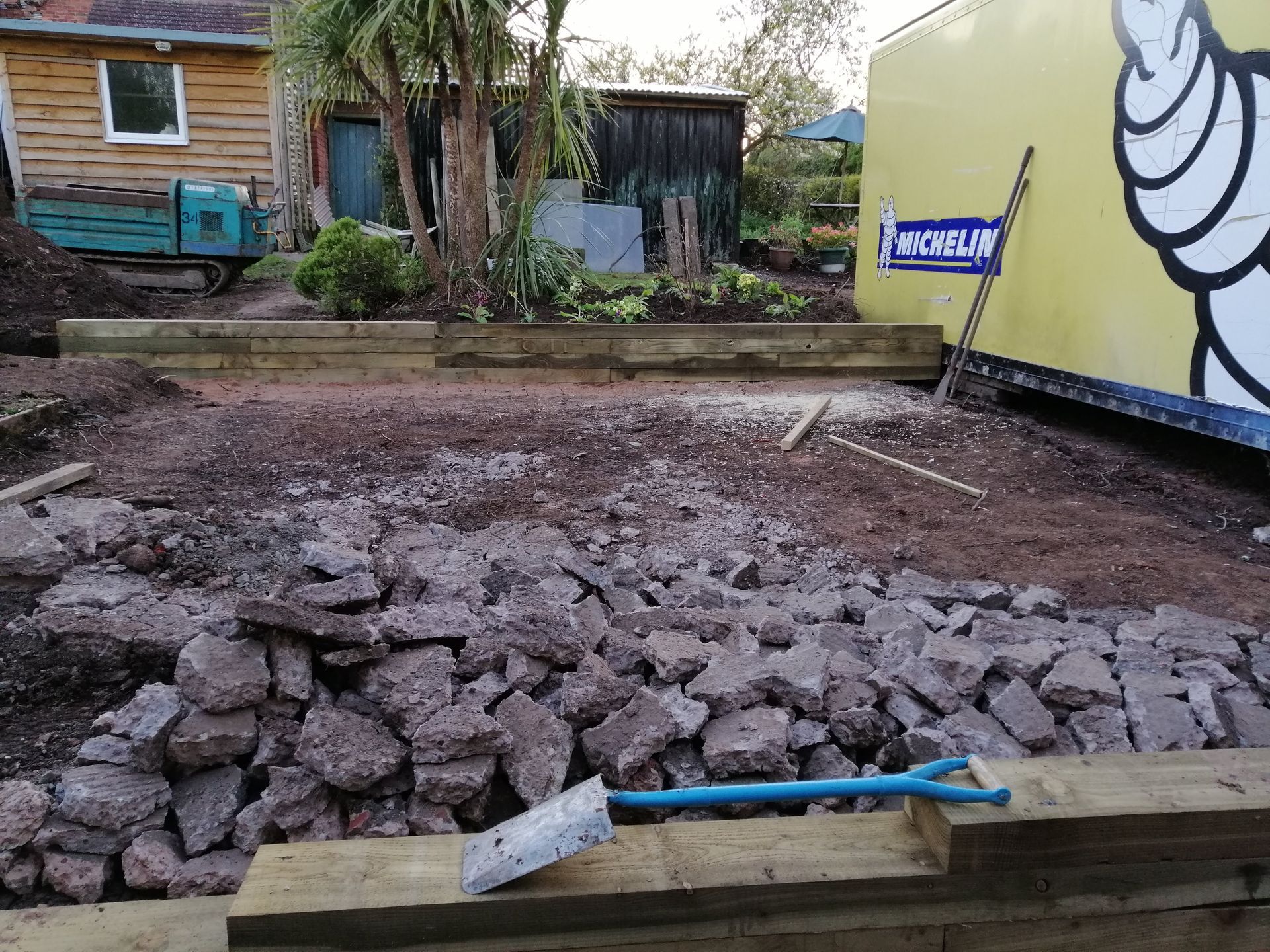 A yellow truck with a michelin logo is parked next to a pile of rocks.