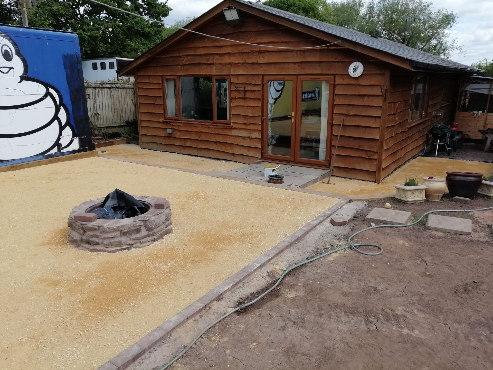 A wooden house with a fire pit in front of it.